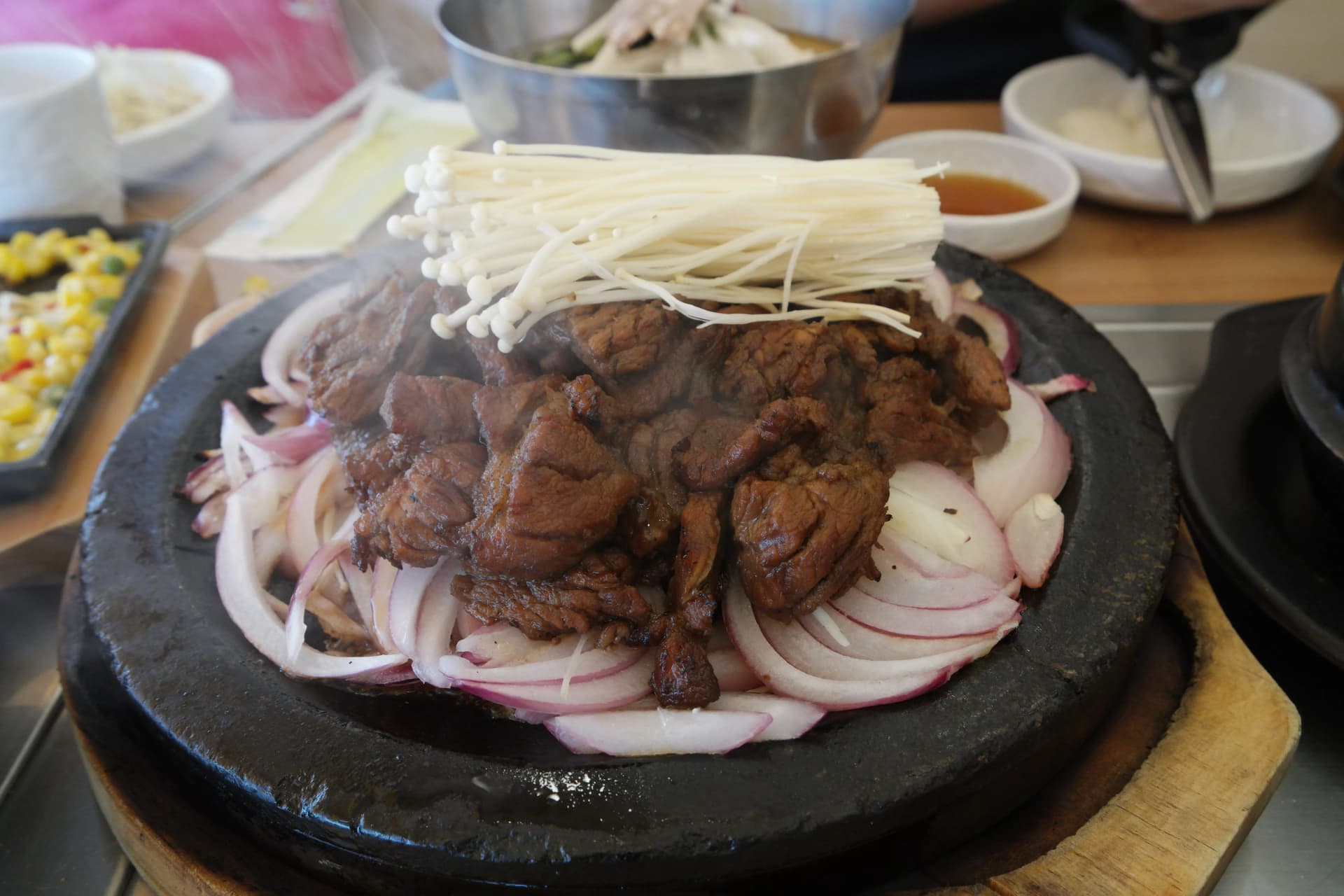 ሶክጋልቢ ዋና ምግብ — ሙቅ ድንጋይ ሳህን ላይ የከሰል ጥብስ ጎድጓዳ ስጋ ሽንኩርትና ፓኢ ቡቃያ እያጠበሰ ሲዘረዘር | 하이제이에스비