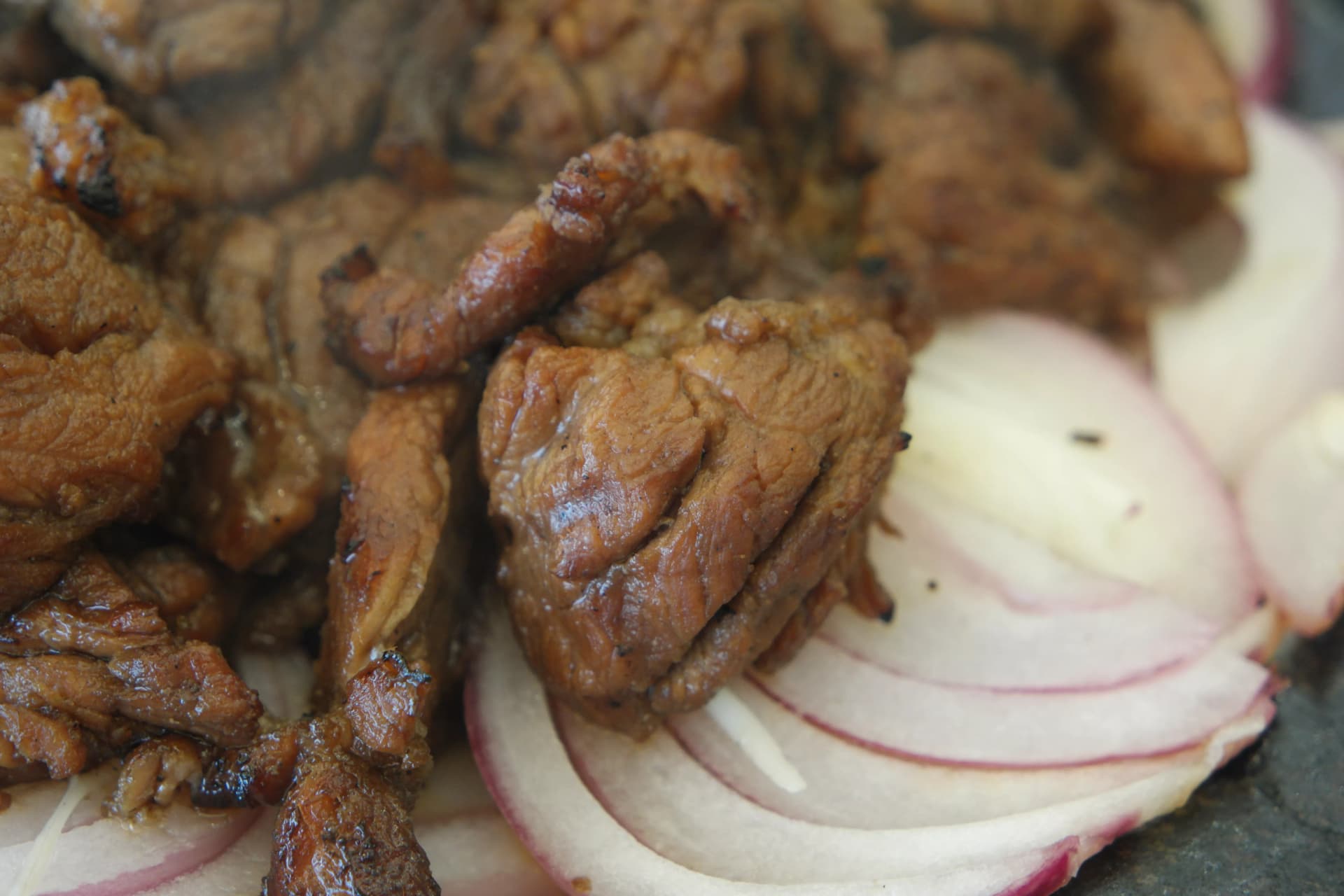 ሶክጋልቢ ቅርብ ምስል — ከሰሉ ዘልቆ ሸካራ ጥራቱ ልዩ ሆኖ የሚታይ ጎድጓዳ ስጋ ድንጋይ ሳህን ላይ ሽንኩርት ይጠበስ አብሮ | 하이제이에스비