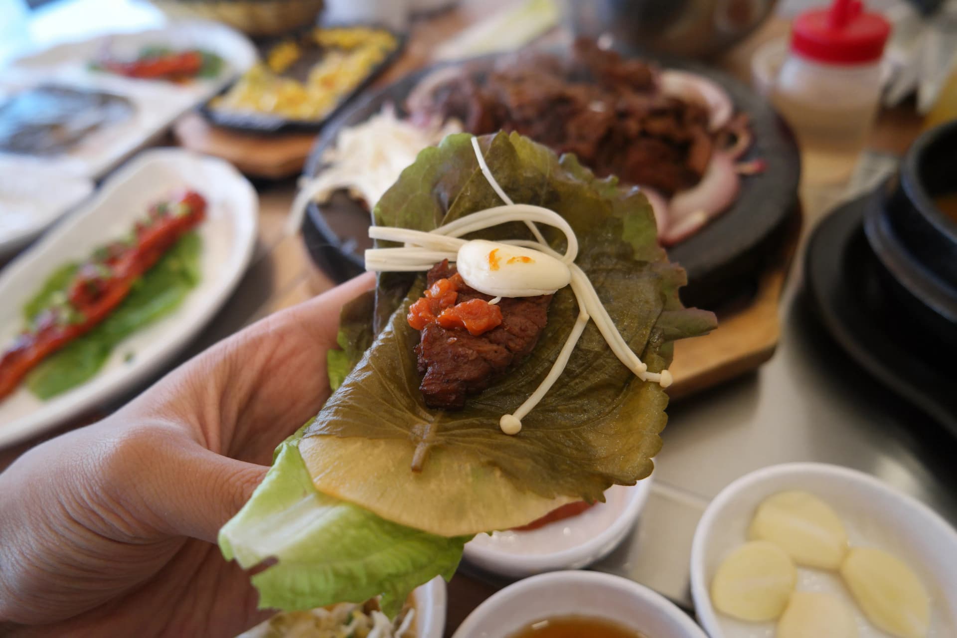 ኮሪያዊ ሳም የምግብ ዘዴ — ሚጥሚጣ ቅጠልና ሰላጣ ላይ አንድ ቁራጭ ሶክጋልቢ፣ ሳምጃንግ ሾርባና ፓኢ ቡቃያ ጠቅልሎ | 하이제이에스비