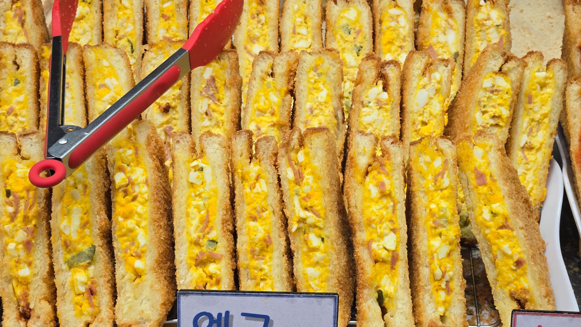 Sandwich-Stand auf dem Seomun-Markt — Auswahl verschiedener koreanischer Markt-Sandwiches in der Auslage | 하이제이에스비