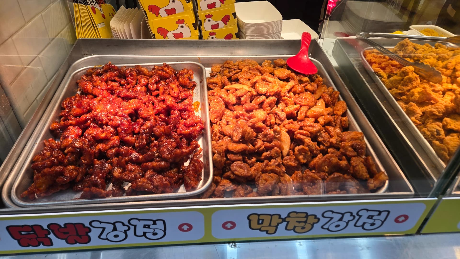 Dakgangjeong-Stand auf dem Seomun-Markt — verschiedene Sorten knuspriges Hähnchen auf Grillplatten | 하이제이에스비