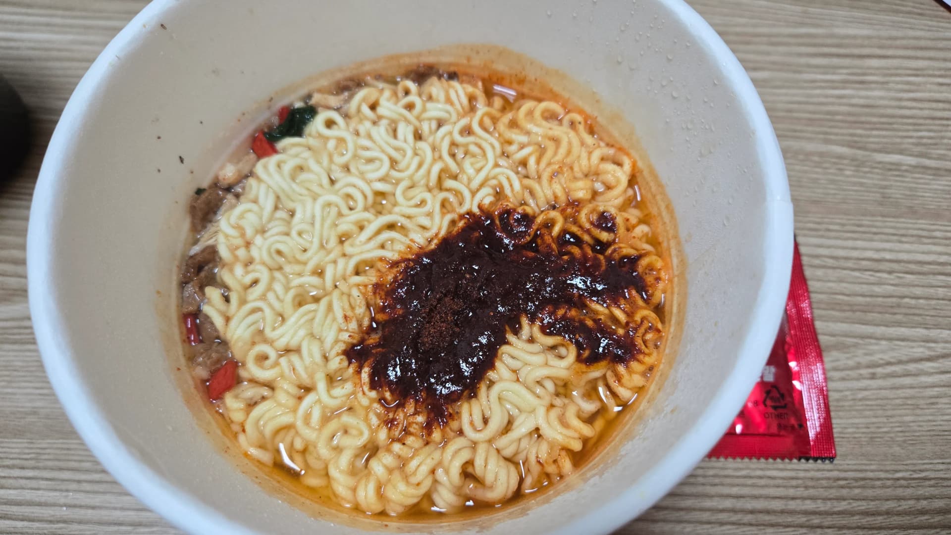 Shin Ramyun The Red cup dopo 3 minuti con coperchio aperto noodle gonfi e brodo rosso intenso