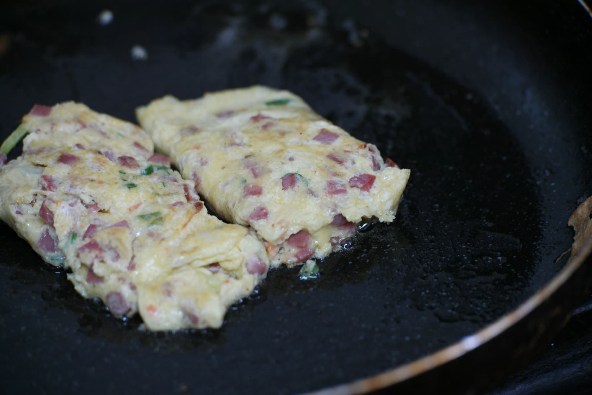Half-folded Korean egg roll being flipped on the pan showing the tricky mid-cook timing