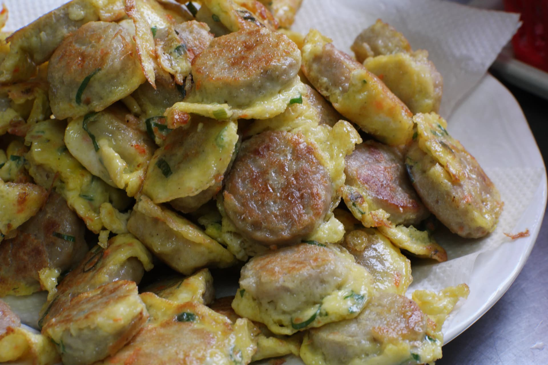 Heaped plate of hand-shaped Korean tofu and meat patties coated in egg batter with uneven homemade texture