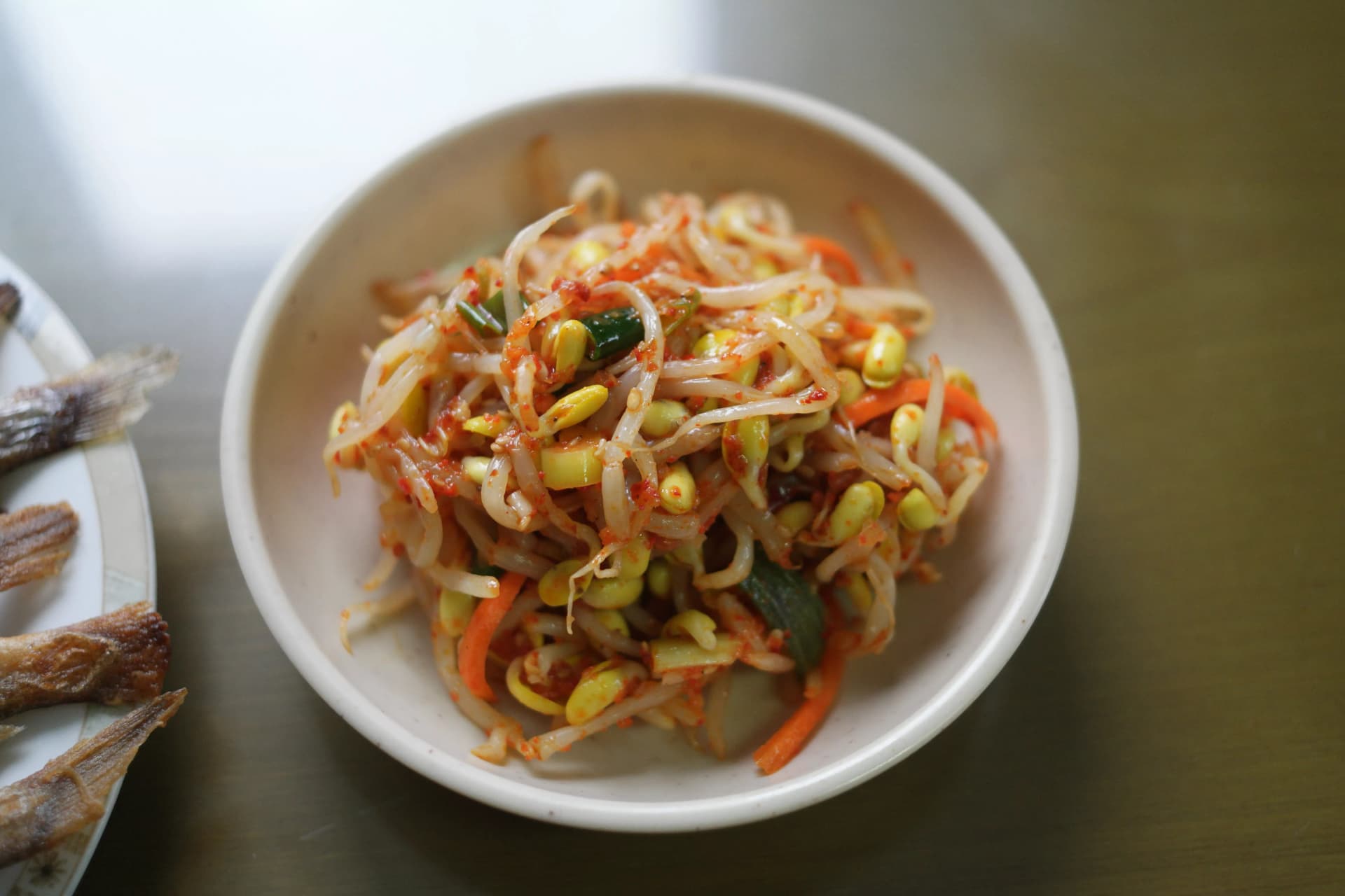 Bowl of Korean seasoned bean sprout salad with red pepper flakes sesame oil spring onion and shredded carrot
