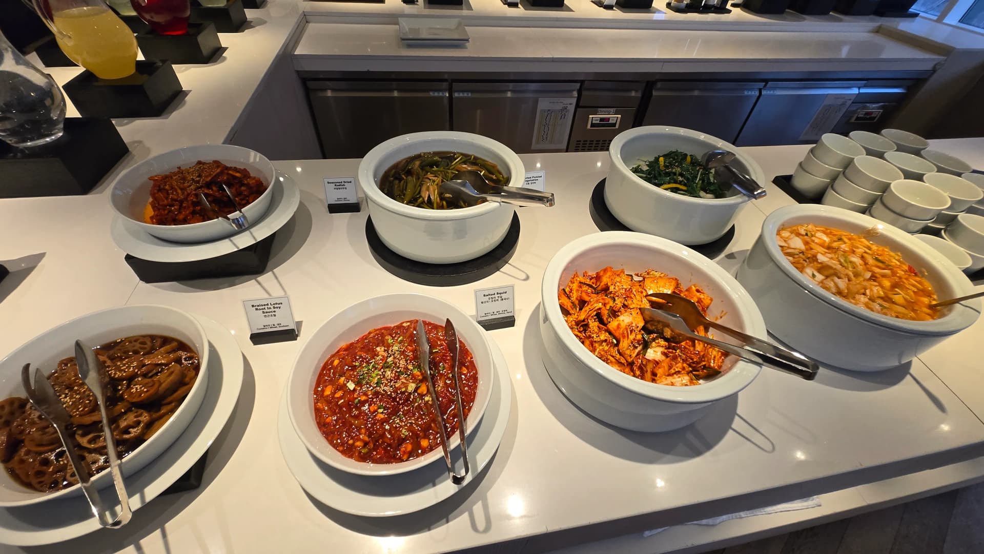 ركن الأطباق الجانبية الكورية في بوفيه الفطور مع كيمتشي ومخللات وسبانخ وجذور لوتس