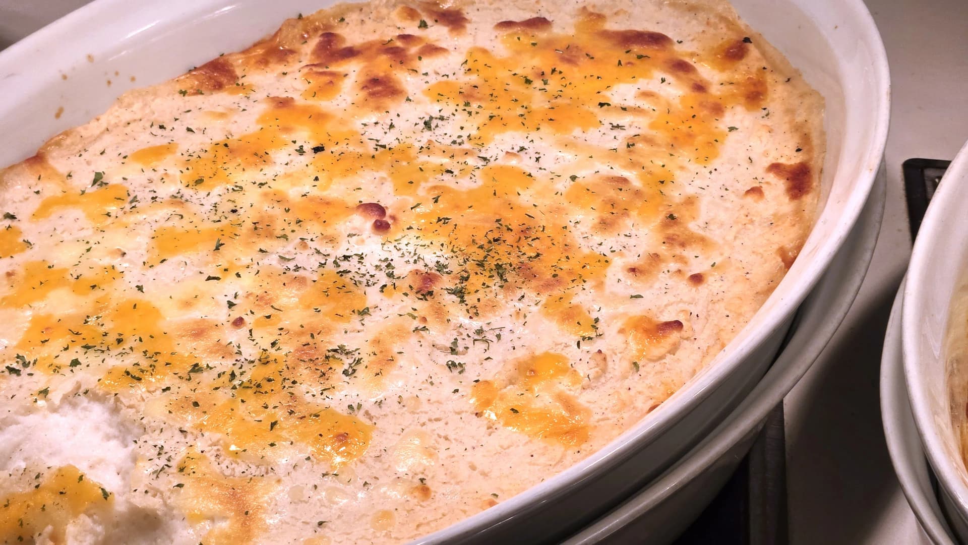 غراتان بطاطس مخبوز بالجبن في بوفيه الفطور بطبقة ذهبية ثقيلة قليلاً