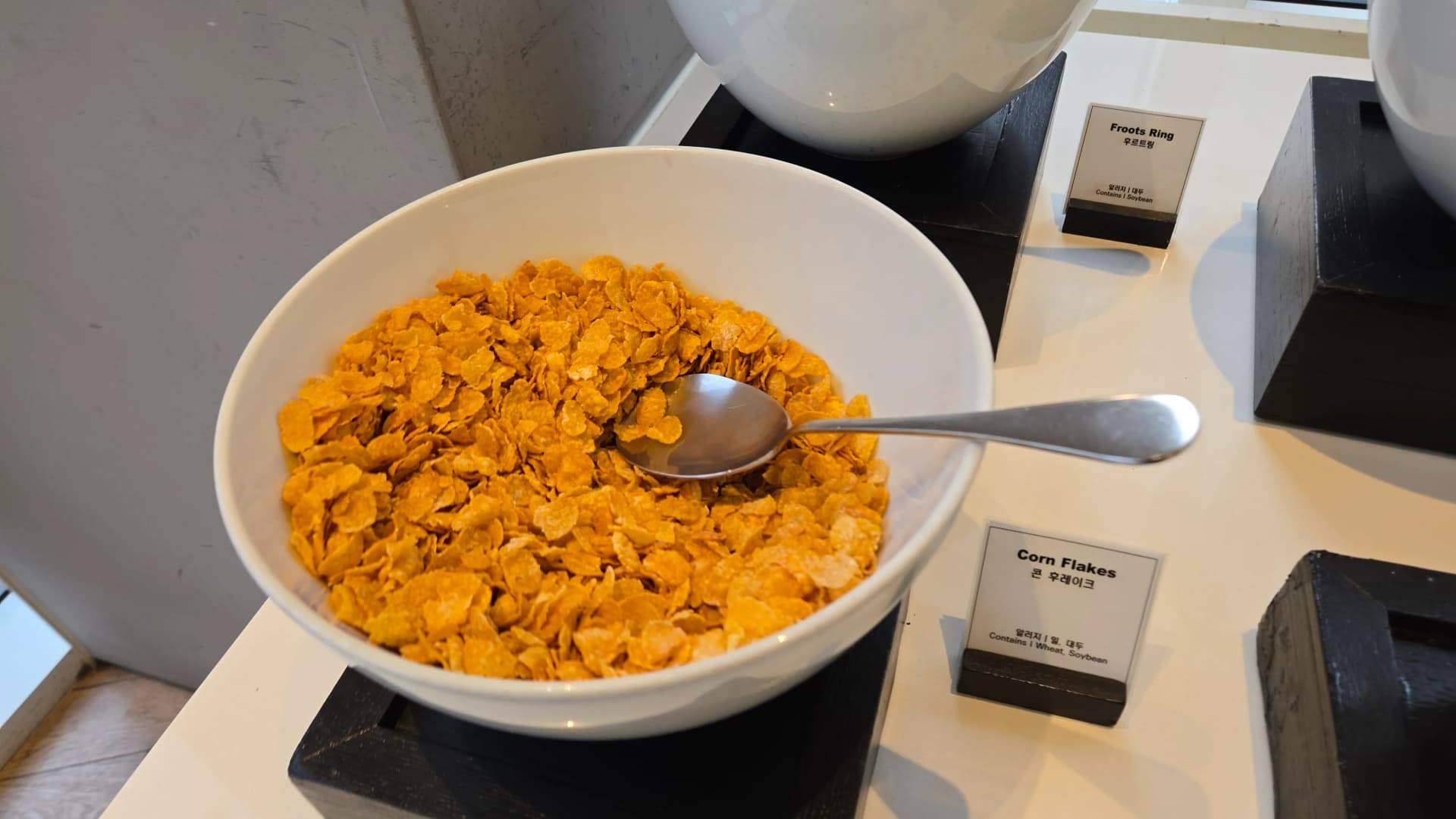 لقطة قريبة لرقائق الذرة في بوفيه الفطور مع معلومات حساسية واضحة