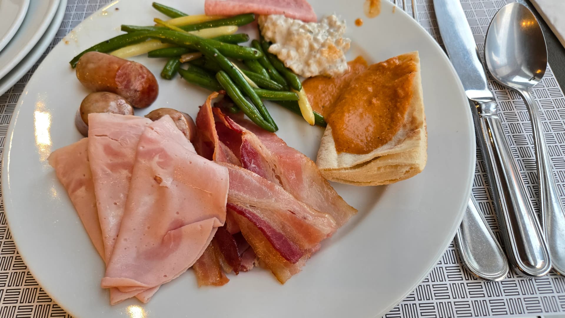 الطبق الأول في بوفيه الفطور مع لحم بارد وبيكون وسجق وغراتان وبانيني