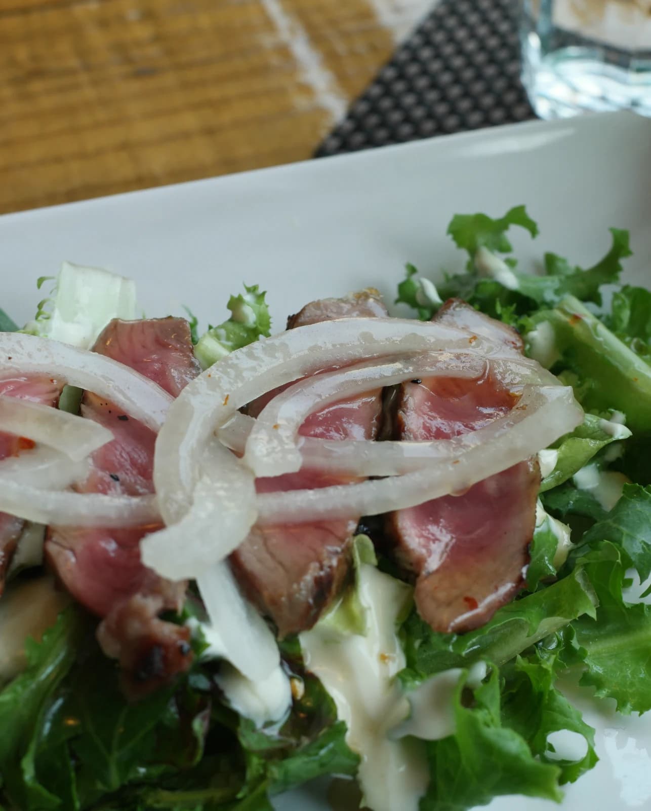 ステーキサラダの近接撮影、肉の断面がミディアムに焼けピンク色が見える