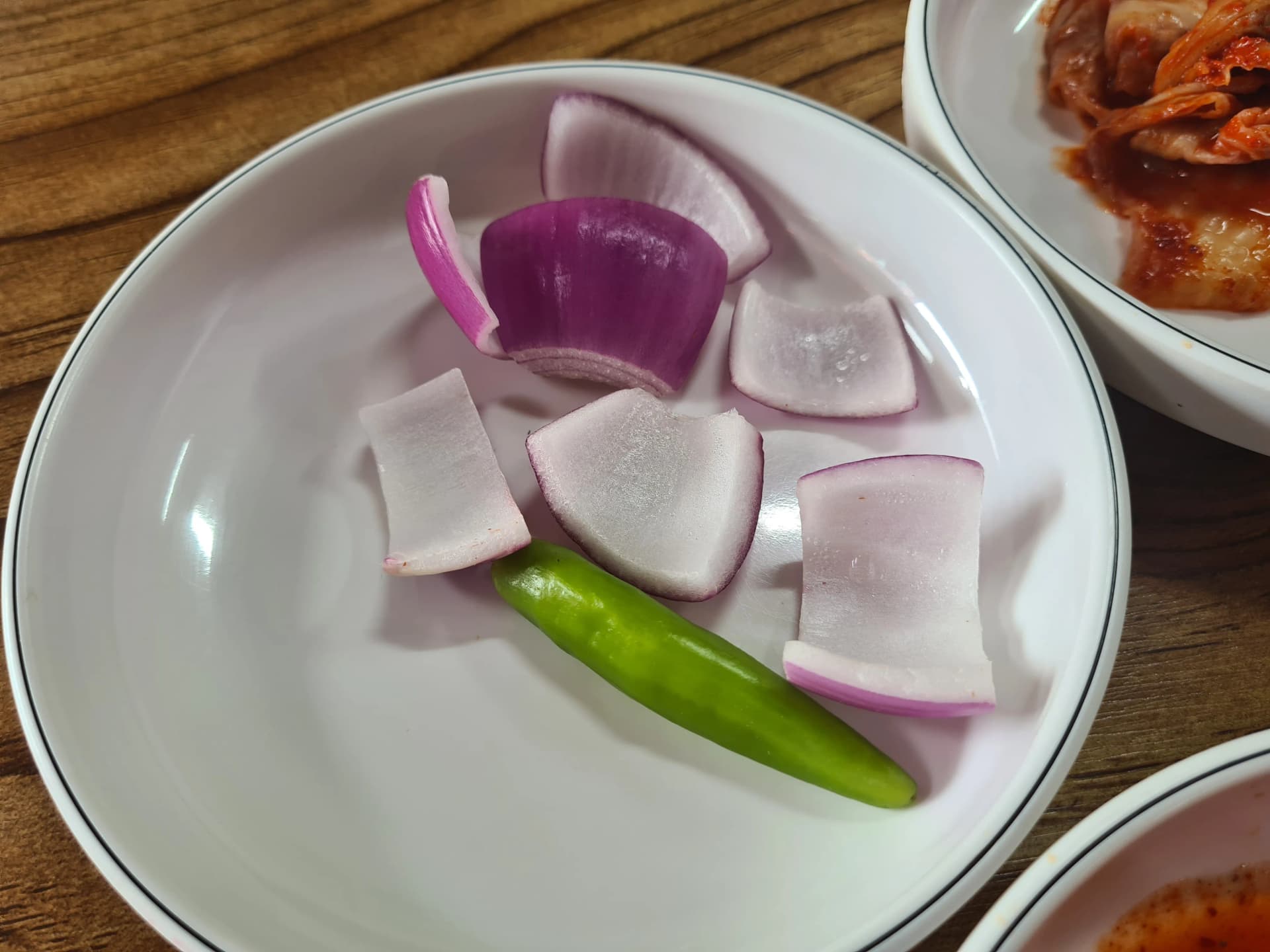 شرائح بصل بنفسجي وفلفل أخضر حار كوري على صحن أبيض — أكل ني لتنظيف الفم بين ملاعق شوربة سوندي غوكباب