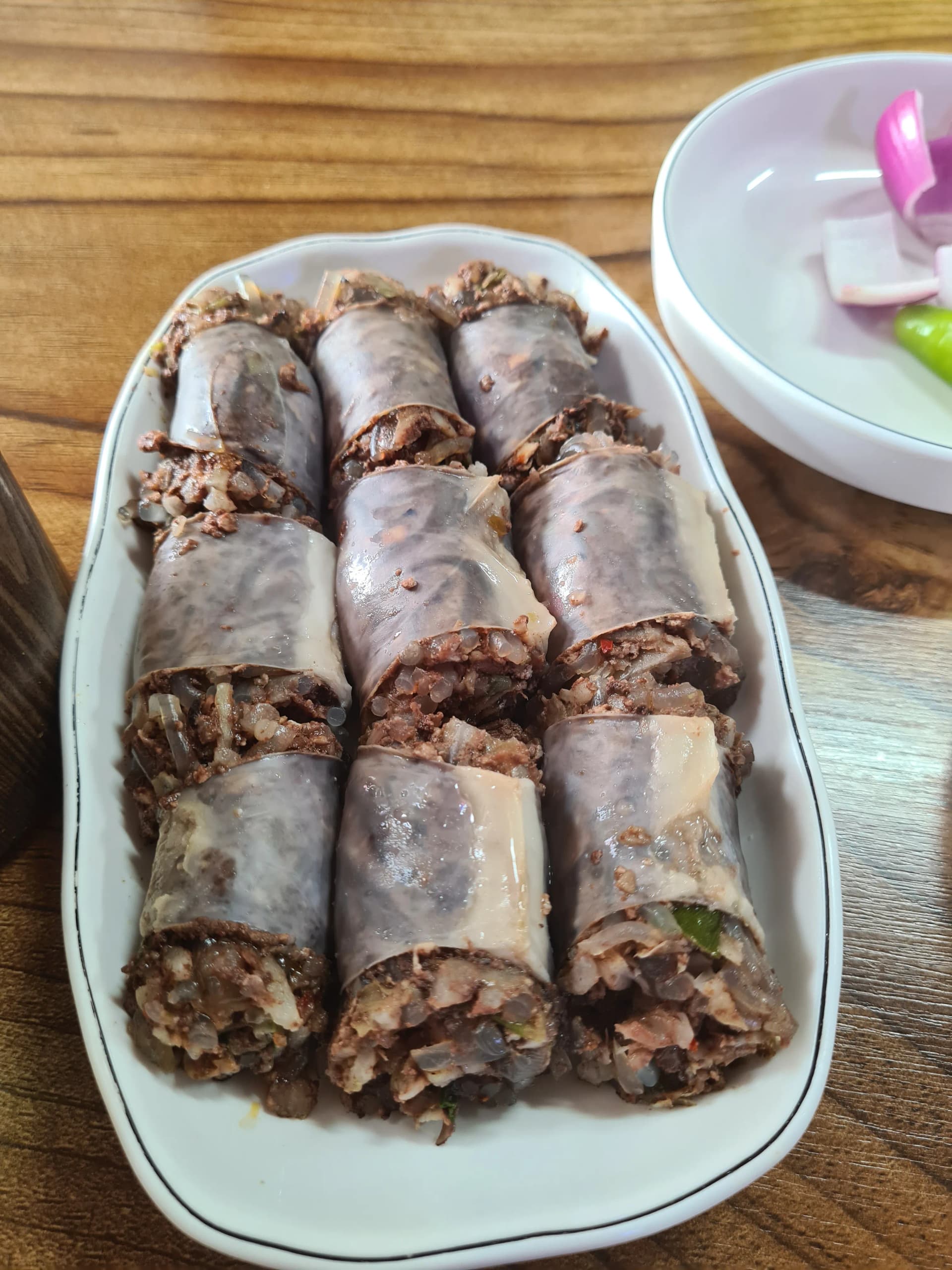 مقطع عرضي قريب لسوندي كوري مصنوع يدوياً — شعيرية زجاجية وخضار ودم خنزير محشوة بإحكام داخل غلاف الأمعاء