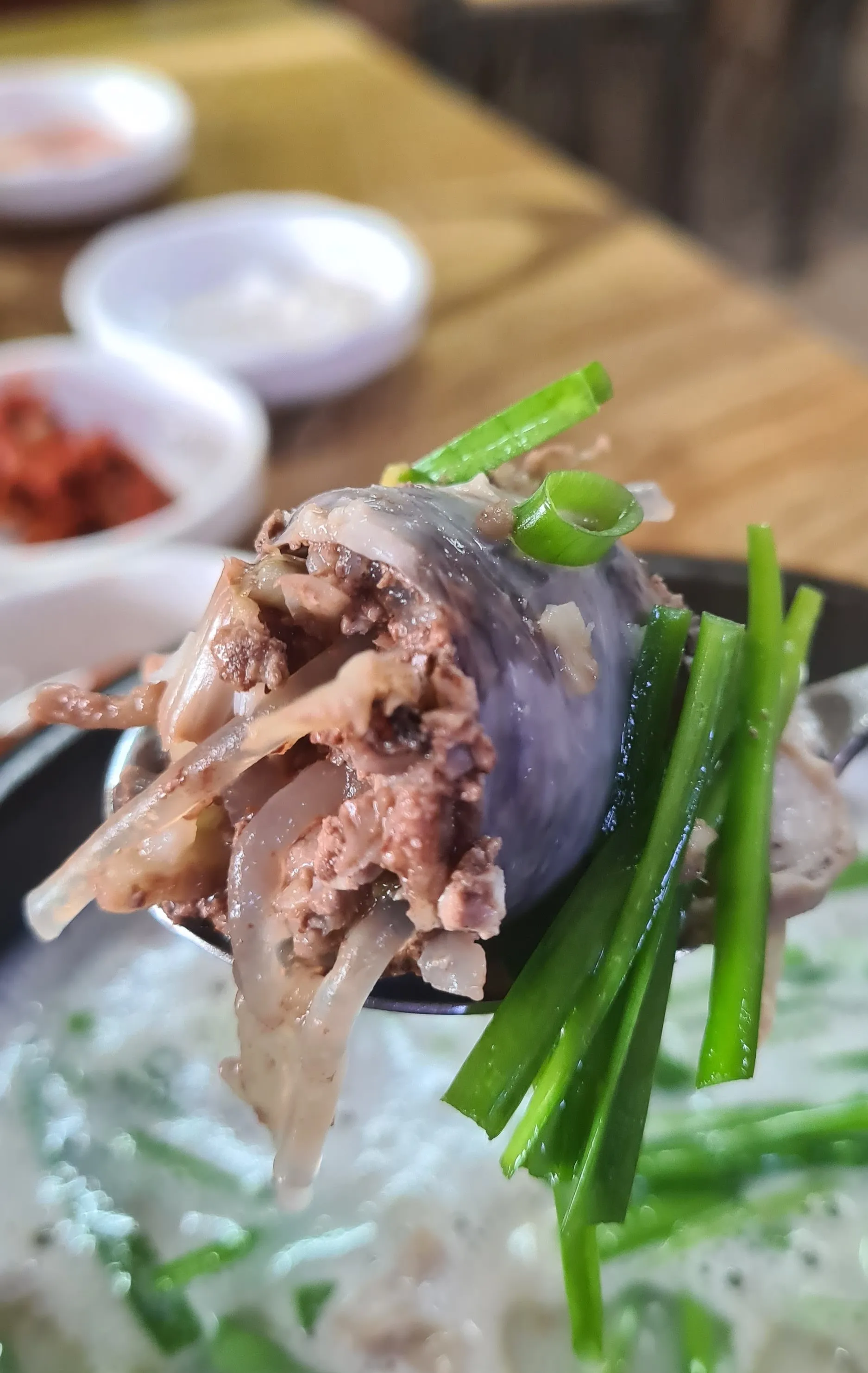 صورة مقربة جداً لمقطع سوندي نقانق الدم محشوة بالشعيرية والخضار بجانب أحشاء خنزير طرية مطبوخة بالمرق