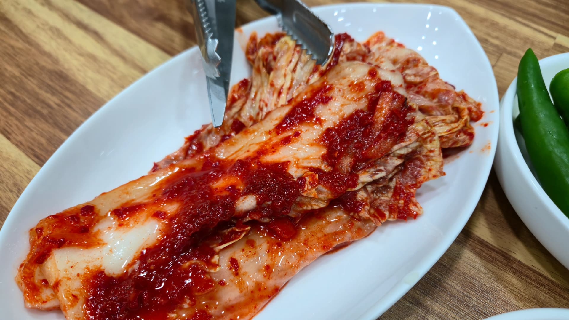 Whole napa cabbage kimchi served uncut at a Korean soup restaurant before being trimmed with scissors