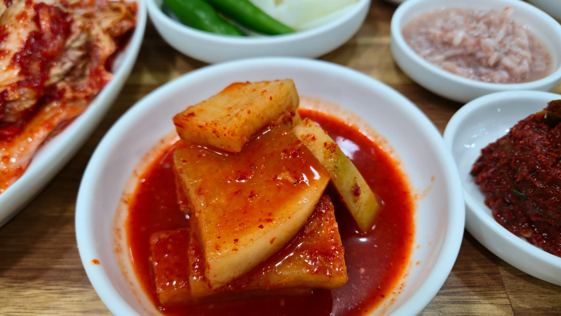 Kkakdugi cubed radish kimchi with a crunchy texture served in a white dish as a pork soup side