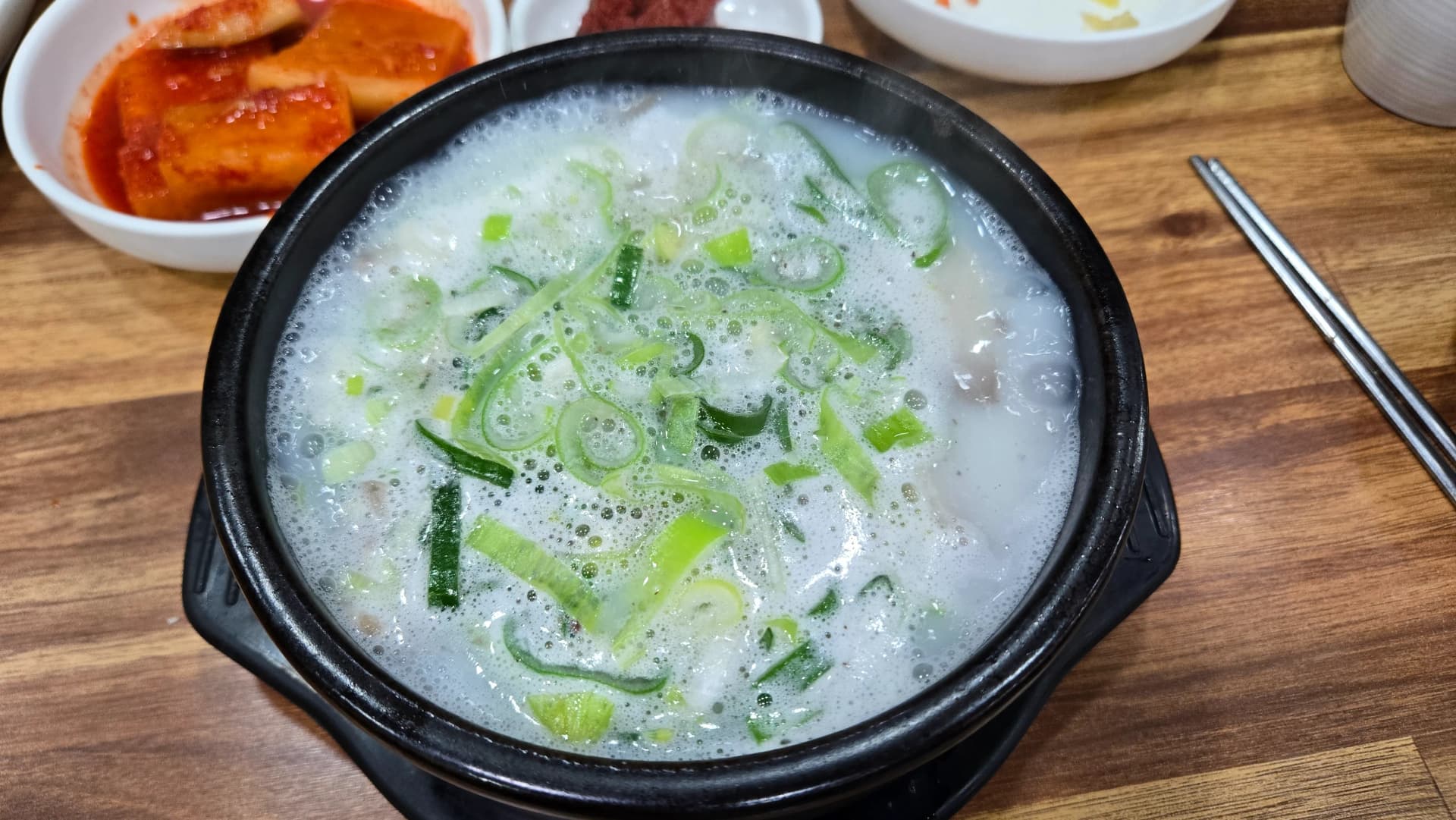Milky white pork bone broth soup in a stone pot showing the long-simmered cloudy broth of sundaegukbap