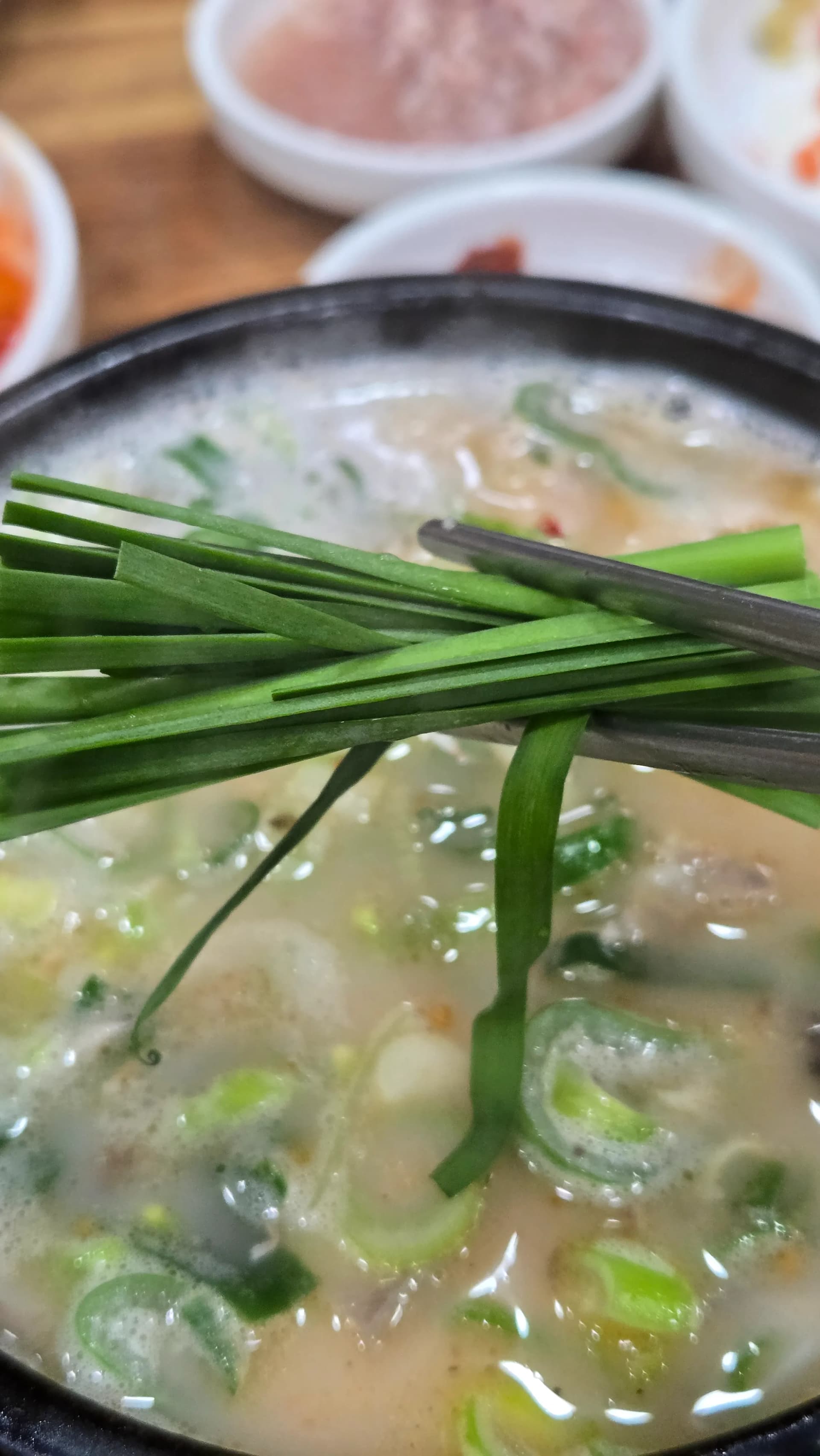 Piling fresh garlic chives generously on top of sundaegukbap before eating