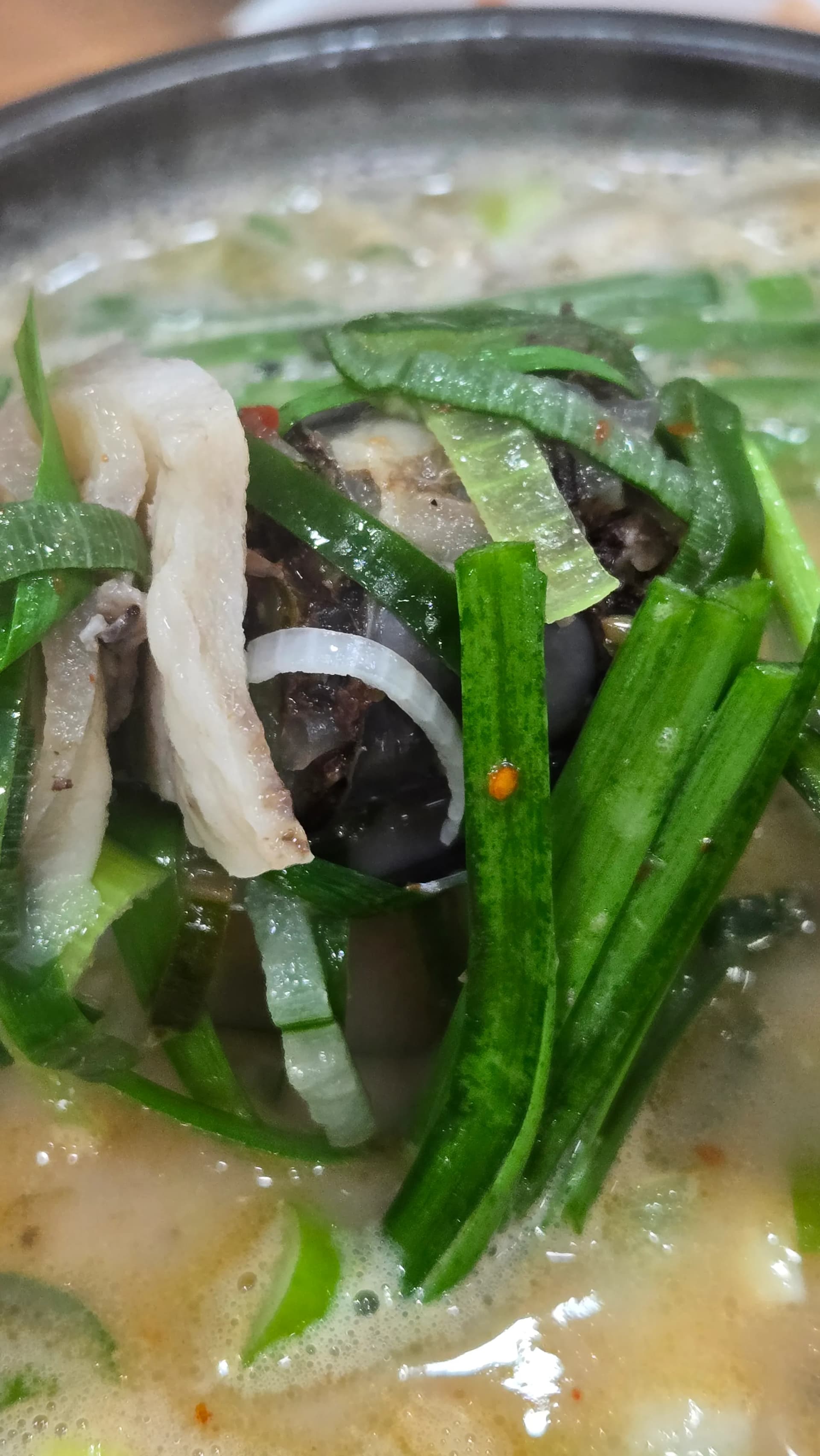 Chives wilting in the hot sundaegukbap broth as the residual heat cooks them down