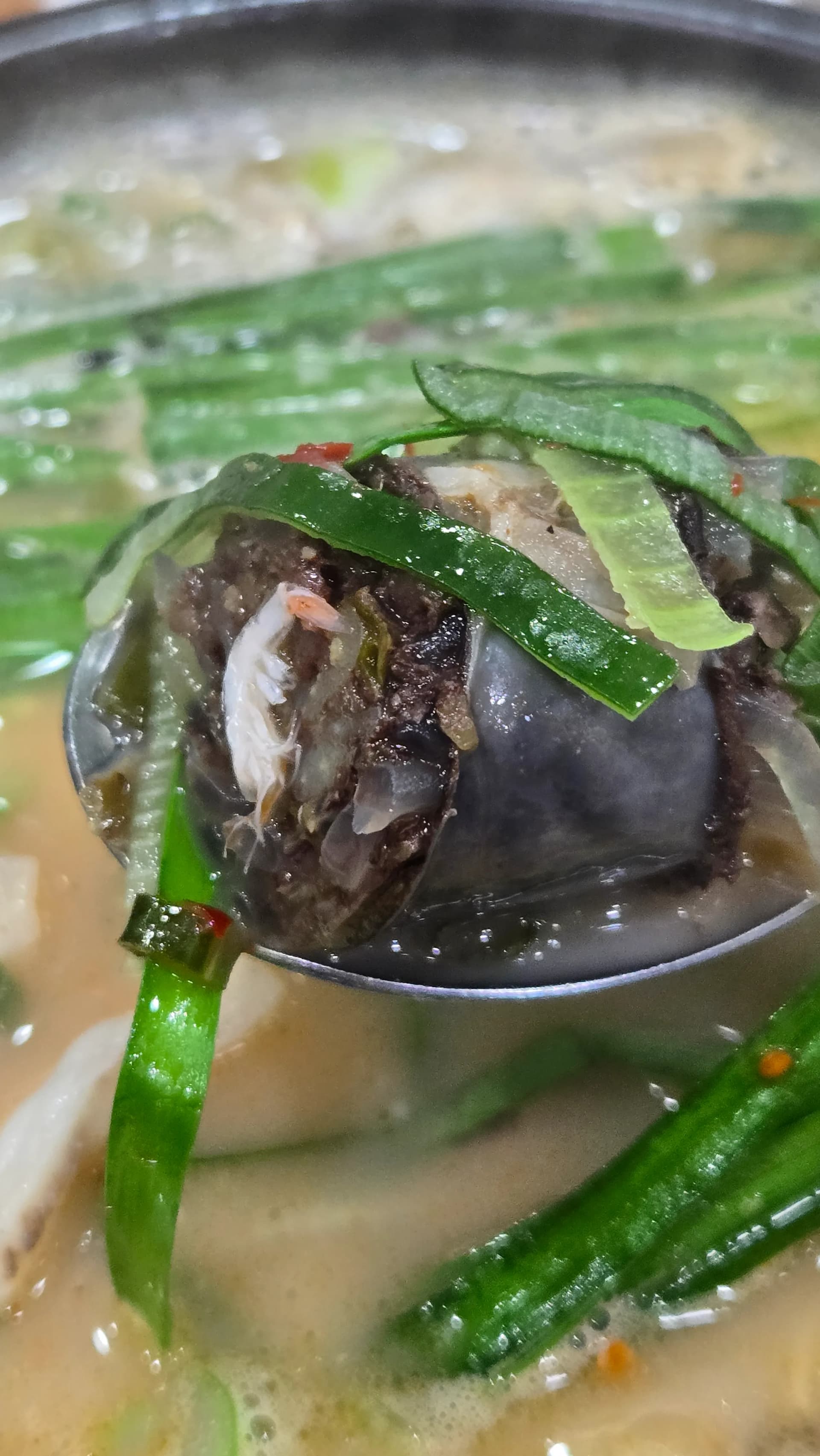 Spooning up wilted chives sundae and boiled pork together in one bite of finished sundaegukbap