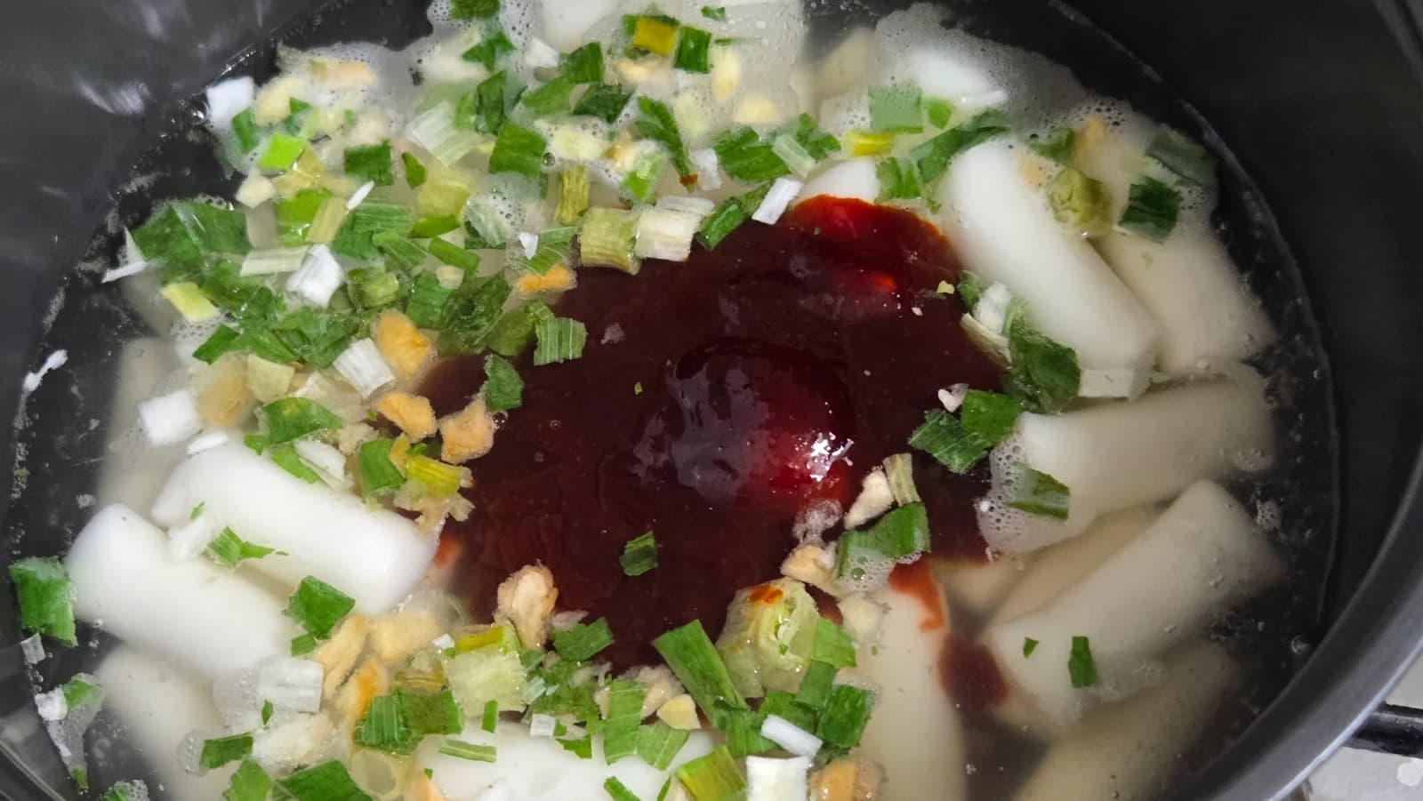 Fehér tészta tetejére nyomott piros gochujang alapú tteokbokki szósz