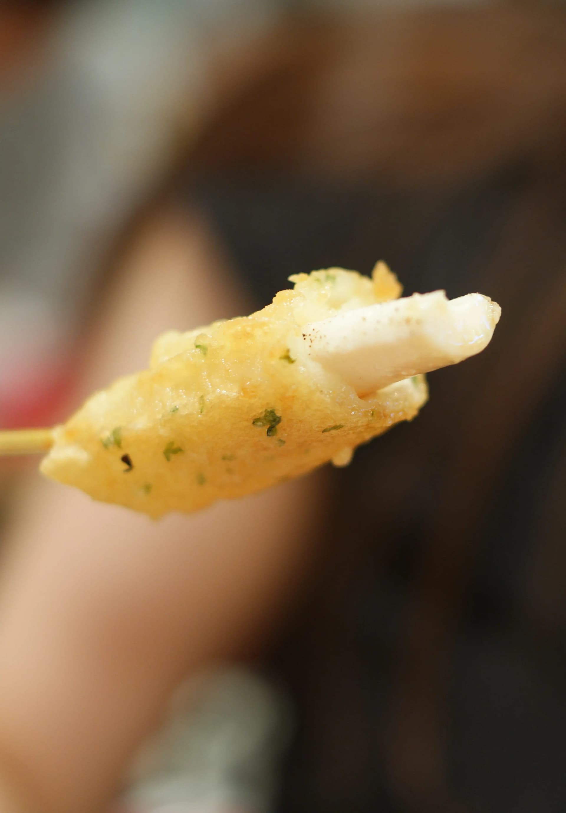 حبار مقلي مرفوع يبين أرجل الحبار البيضاء من تحت العجينة المقرمشة