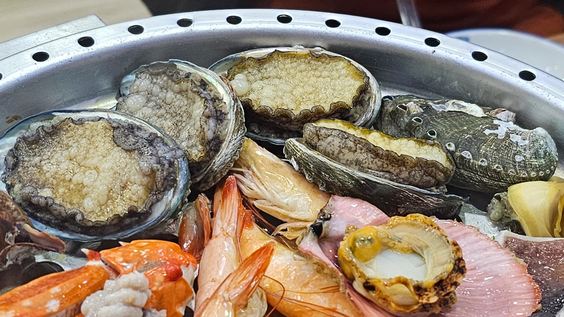 Abulón al vapor en su concha con el jugo burbujeando adentro