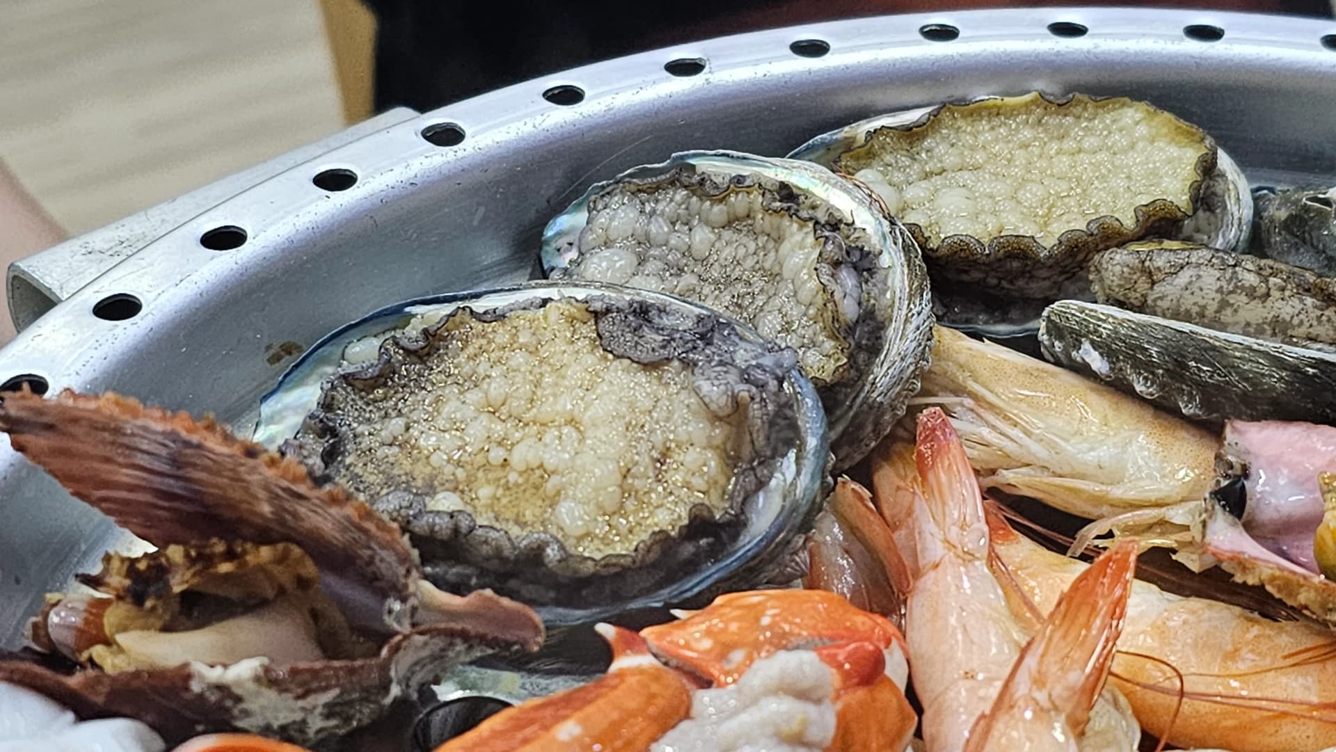 Abulón y camarones al vapor juntos en la bandeja de la vaporera, colores vivos de los mariscos frescos