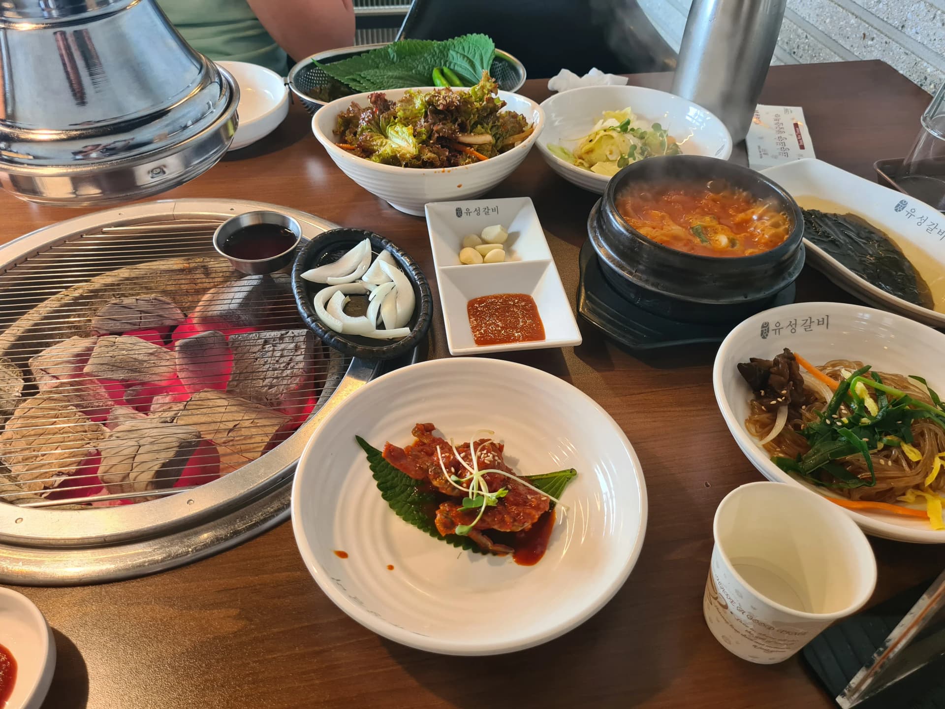 طاولة مطعم يوسونغ غالبي مليئة بالأطباق الجانبية من حساء ميسو وجابتشاي وخضروات لف وريش متبّلة للتذوق