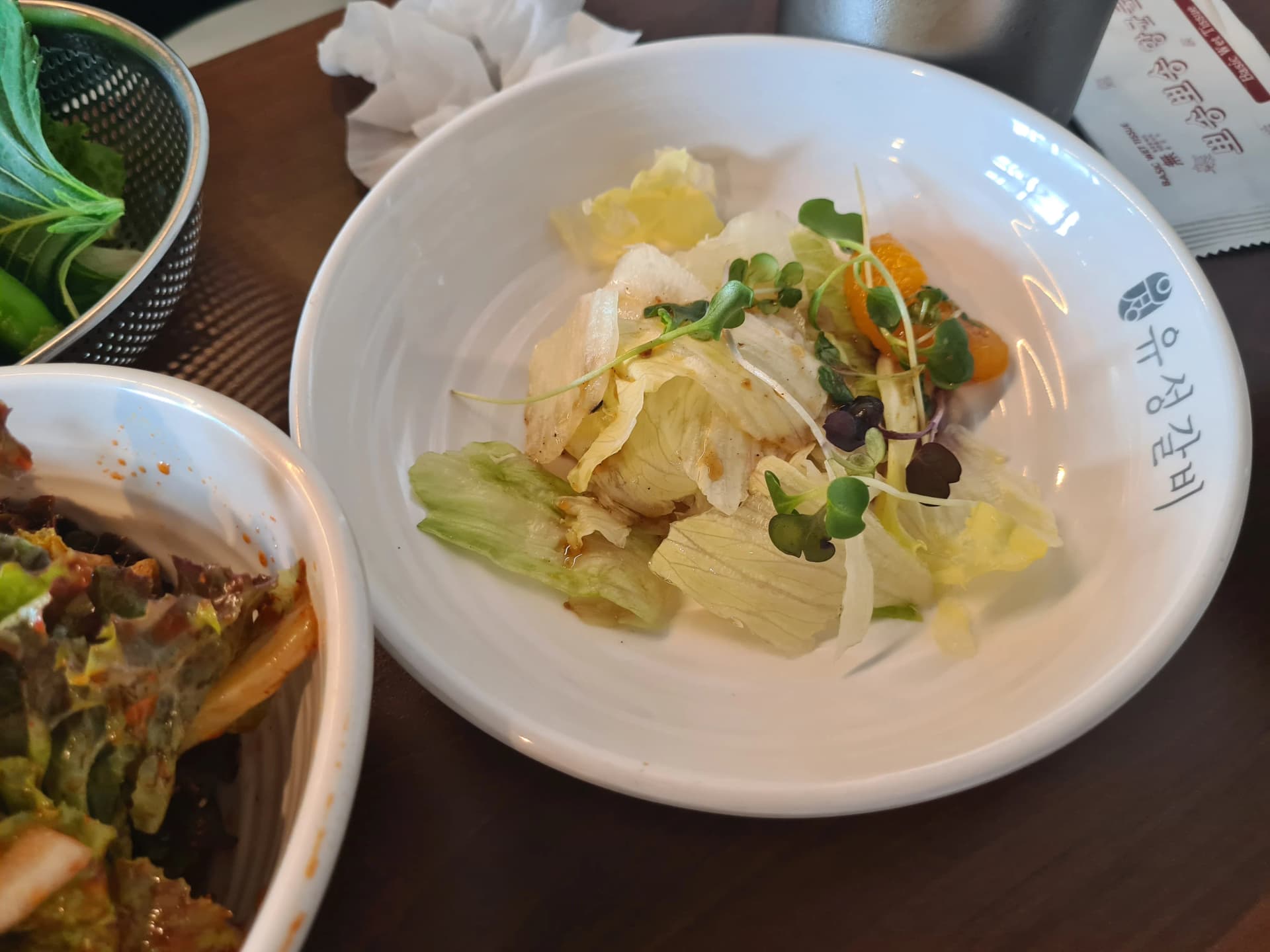 سلطة ملفوف بصلصة حامضة مع شريحة يوسفندي وبراعم فجل في مطعم شواء كوري