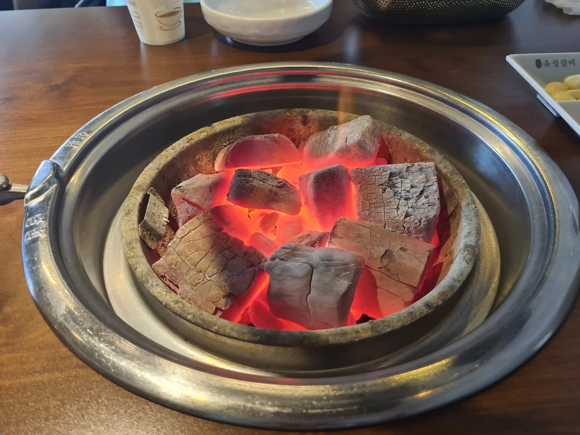 فحم بلوط طبيعي متوهج باللون الأحمر على شواية مطعم يوسونغ غالبي