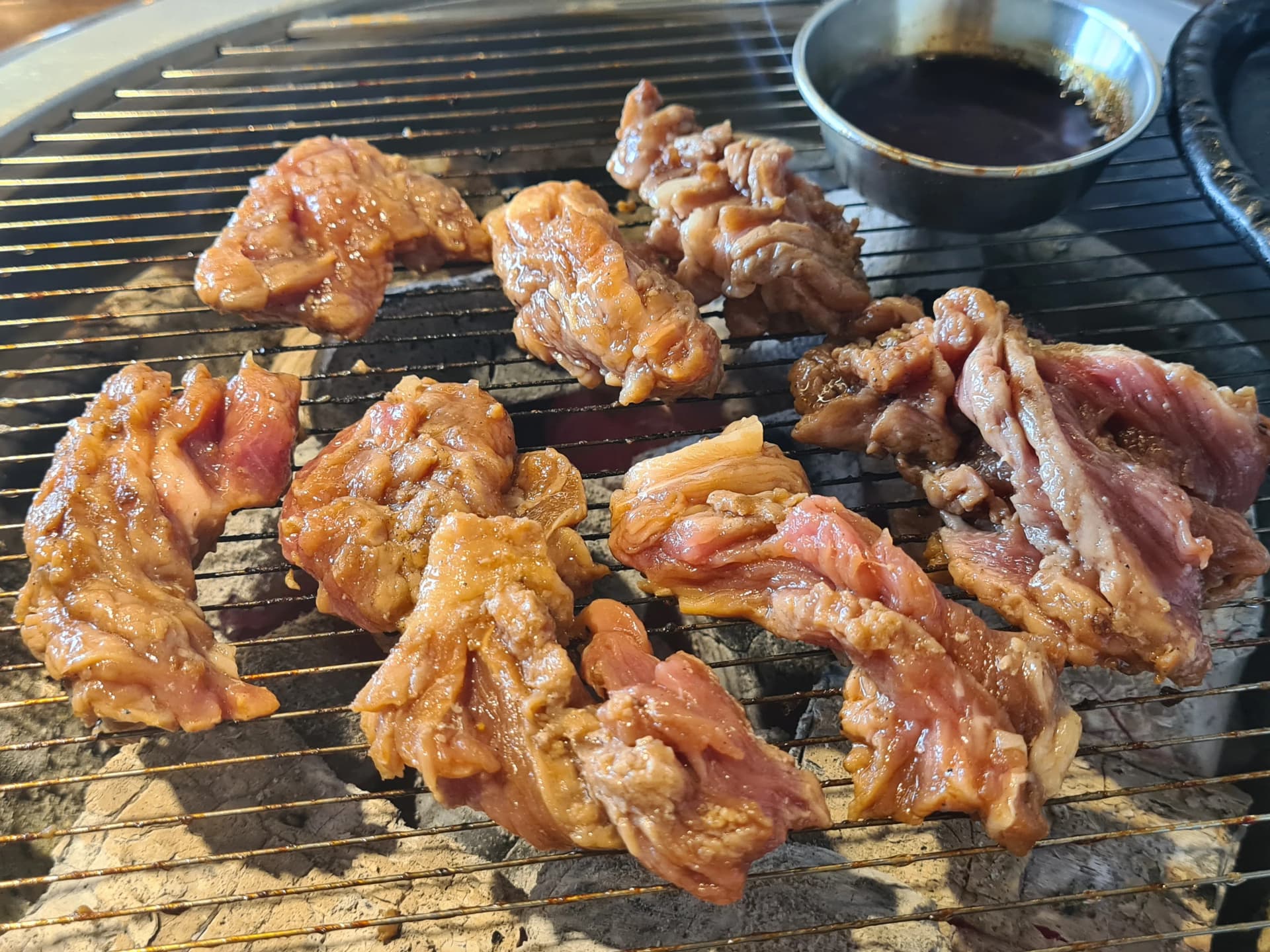 ريش لحم متبّلة في منتصف الشوي — التتبيلة بدأت تتغيّر لونها مع الحرارة