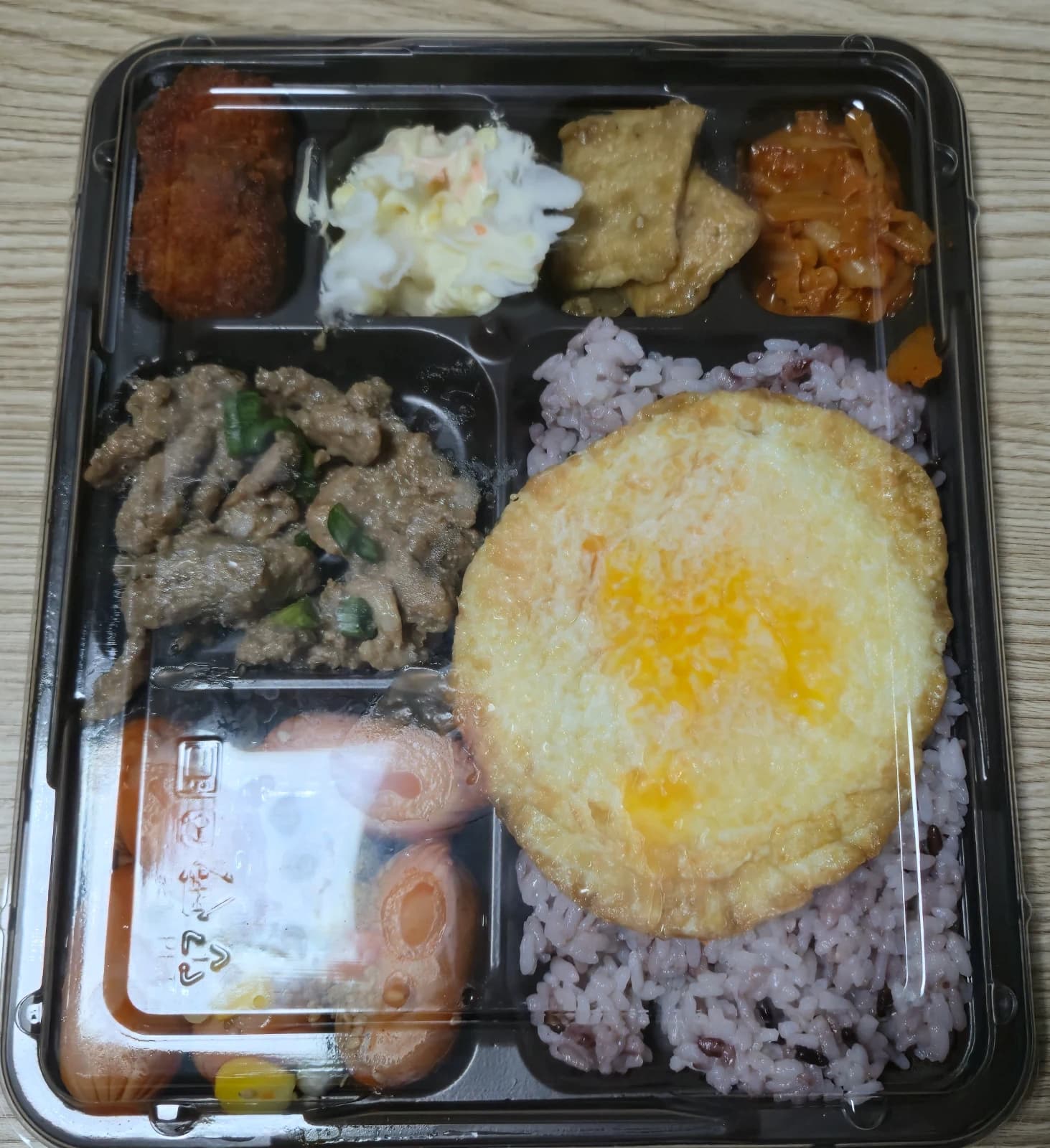 Bento coreano con etichetta ancora attaccata che mostra contorni e uovo fritto