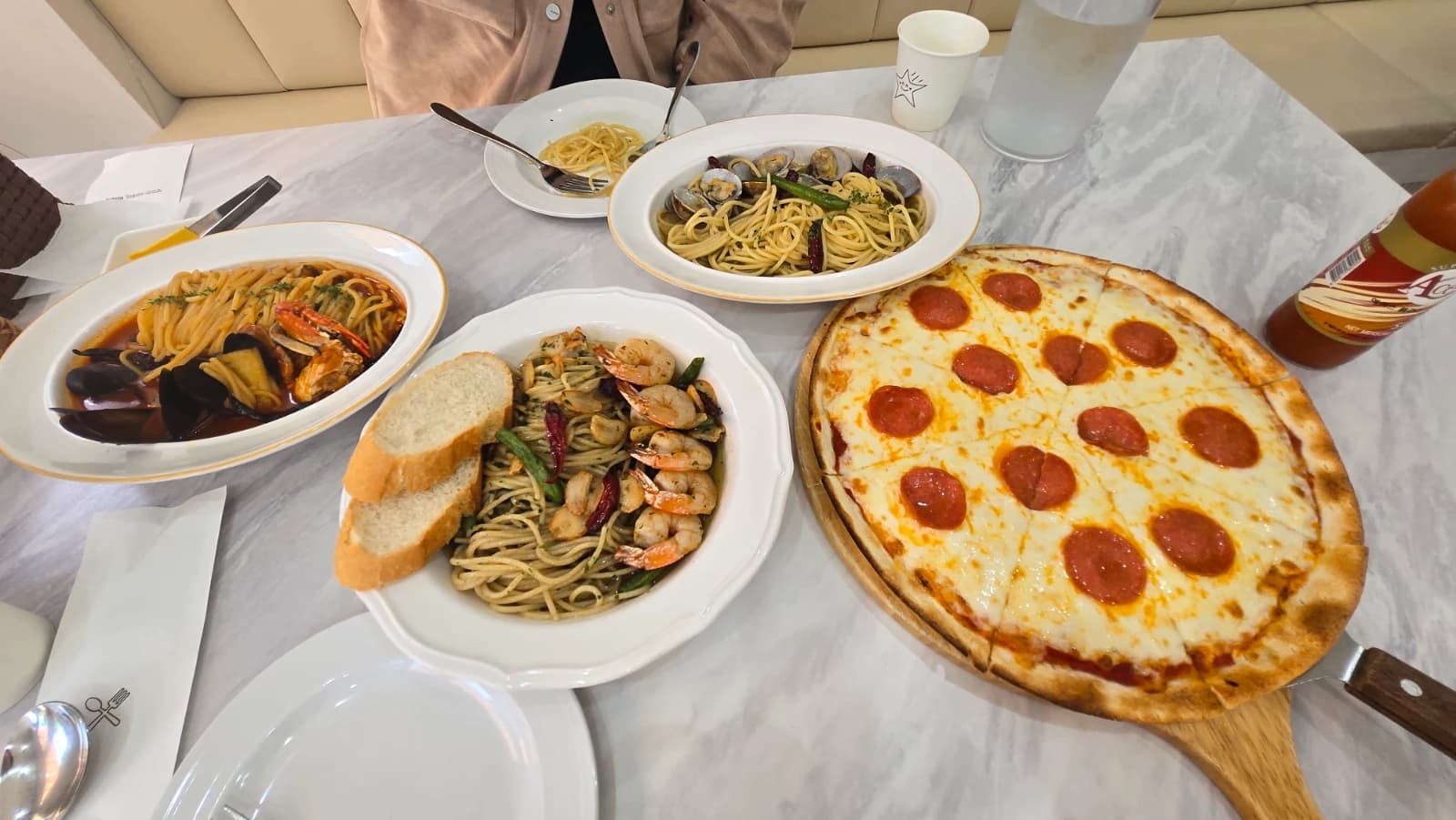 Mitaly table covered with three pasta bowls and a full pepperoni pizza