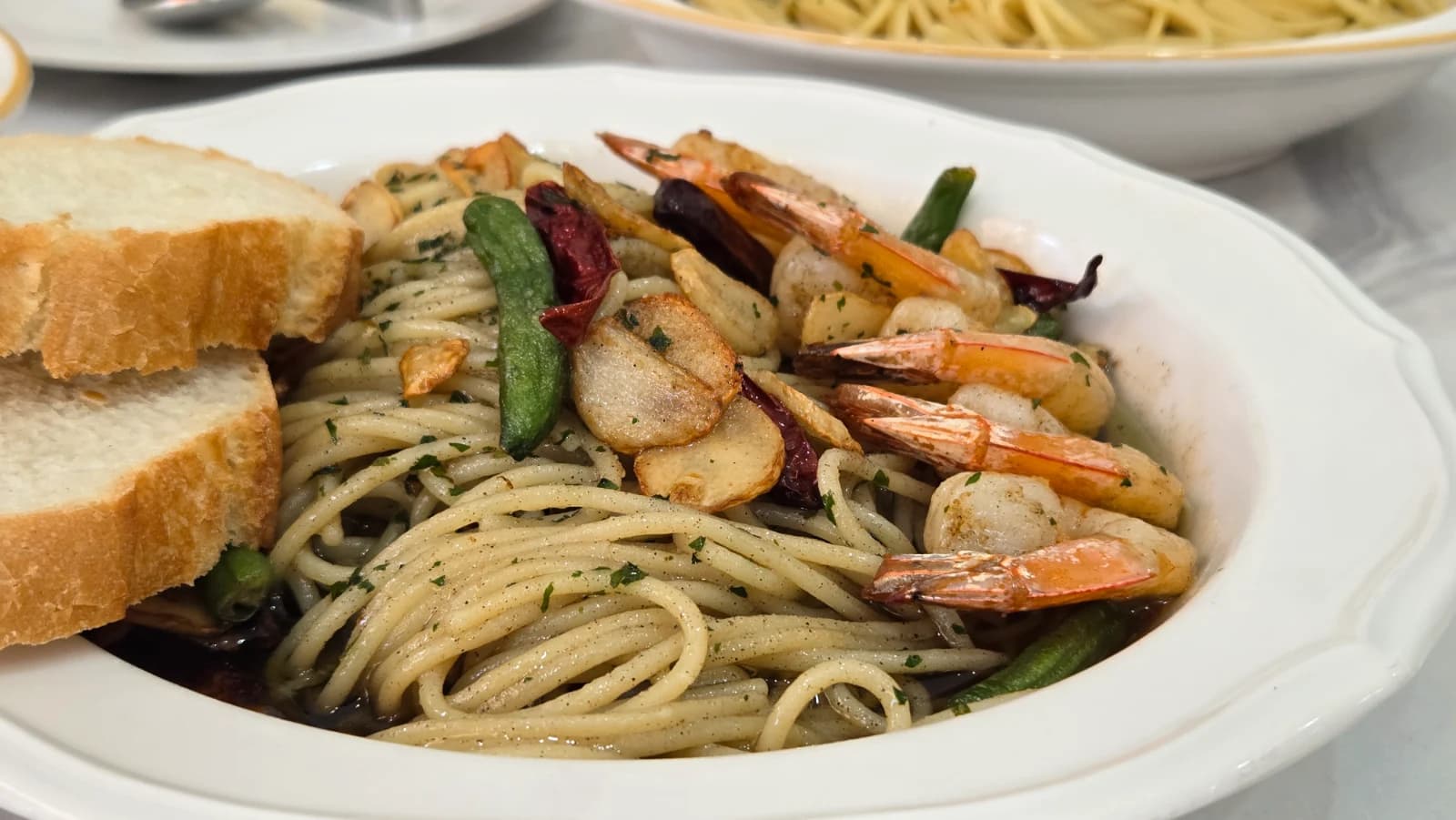 Full plate of Mitaly signature gambas pasta with shrimp and baguette slices