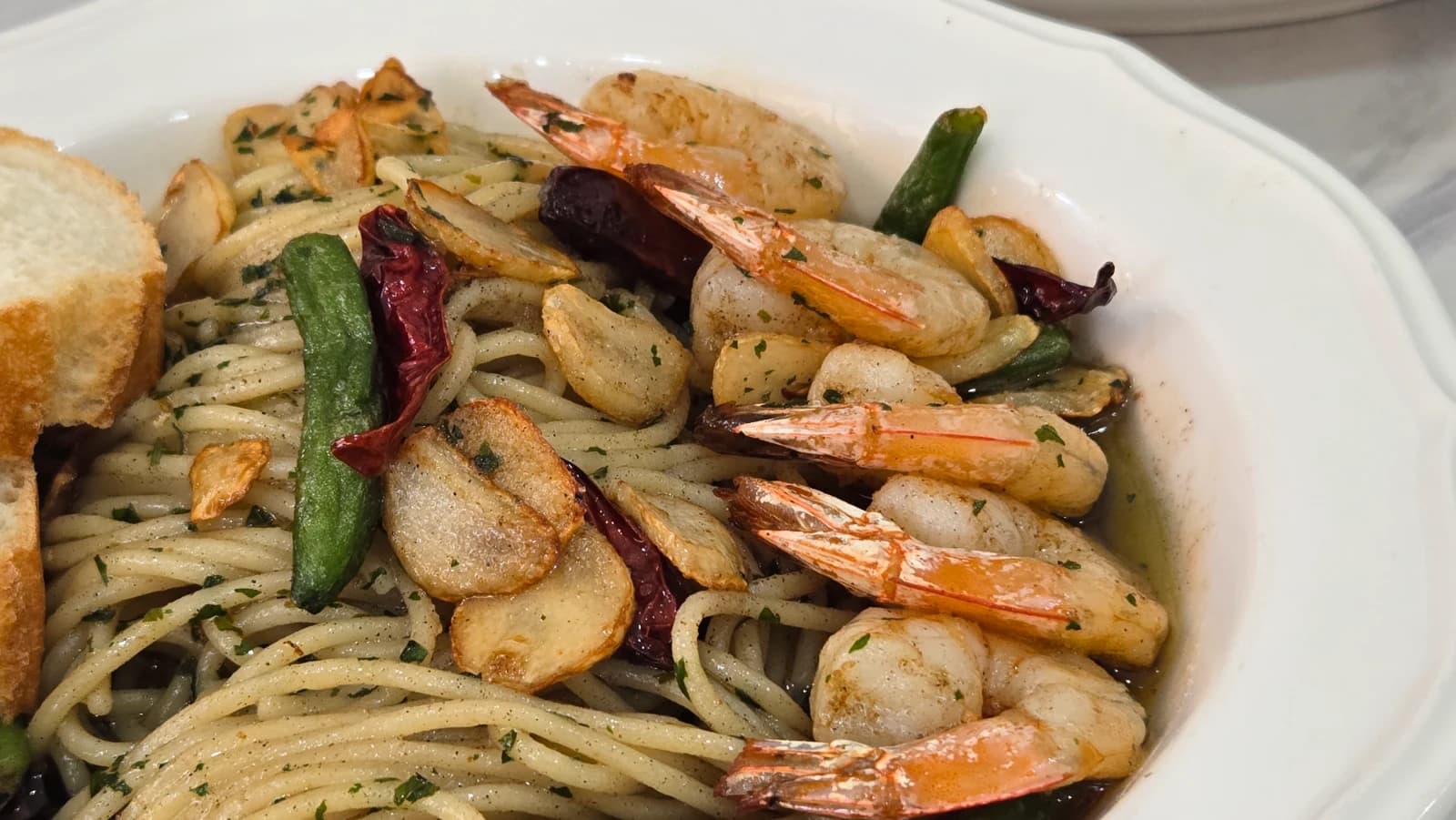 Dipping baguette bread into the garlic oil from the gambas pasta plate