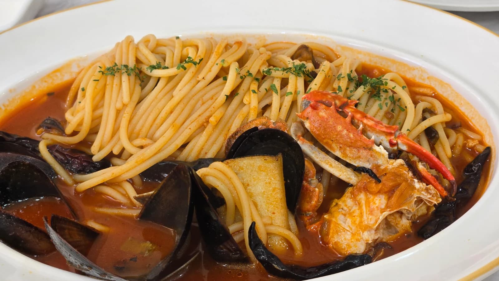 Full plate of Mitaly seafood jjamppong pasta with mussels and crab in red spicy broth