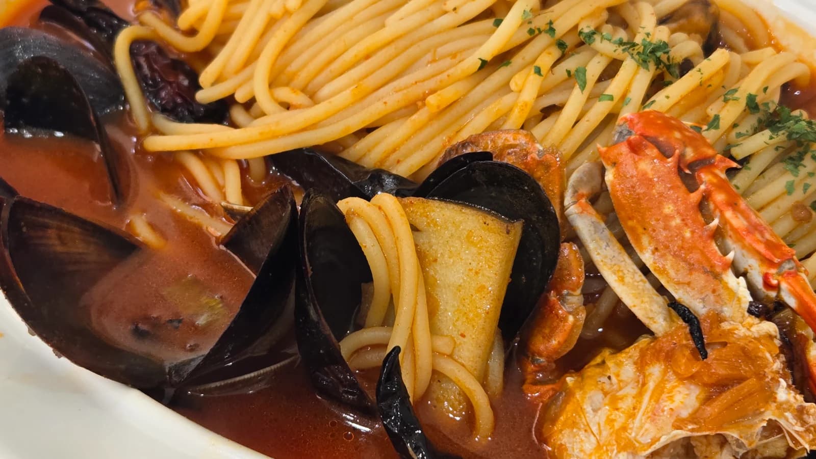 Close-up of jjamppong pasta noodles swimming in spicy red broth