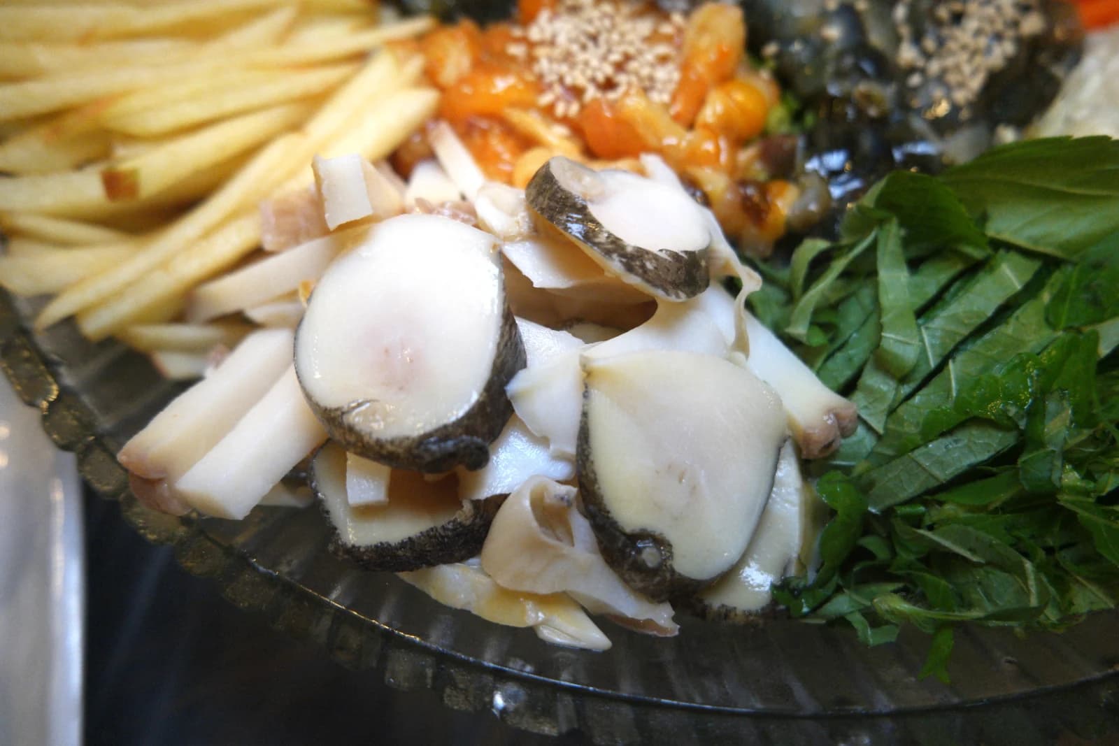 Thinly sliced conch and julienned Korean pear inside mulhoe bowl