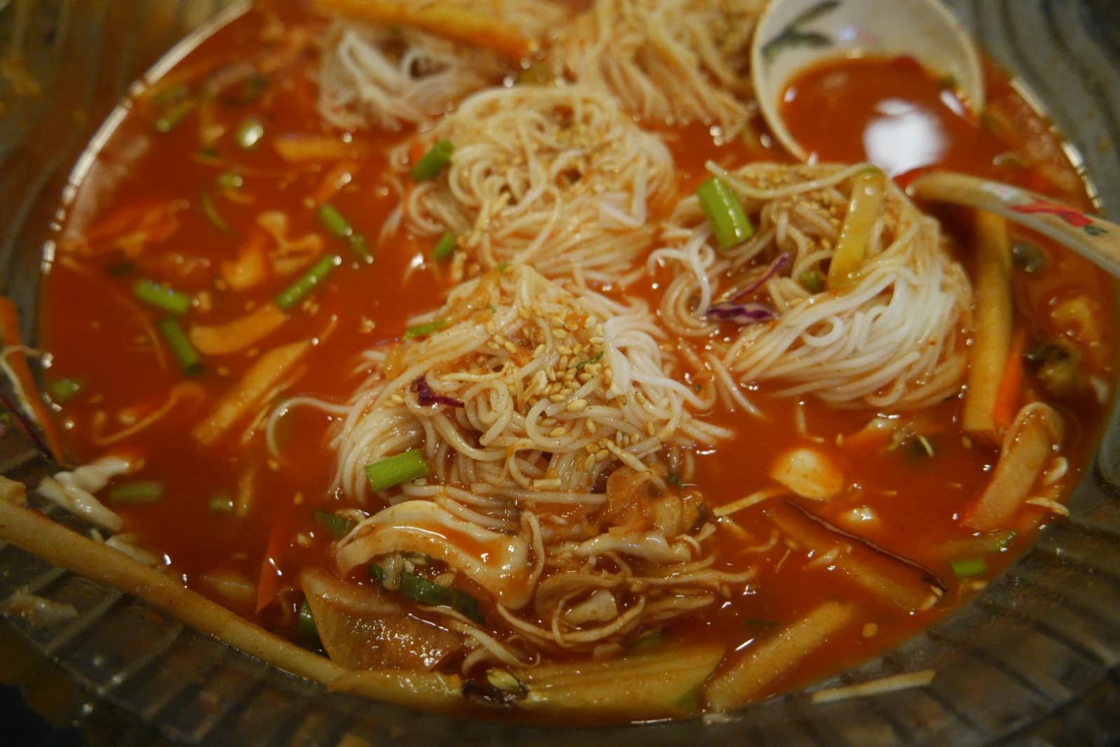 Mixing somyeon noodles into mulhoe broth with chopsticks