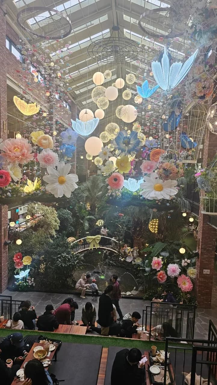 포레스트 아웃팅스 2층 난간에서 내려다본 1층 정원과 분수 연못, 계단형 좌석에 앉은 사람들 | 하이제이에스비