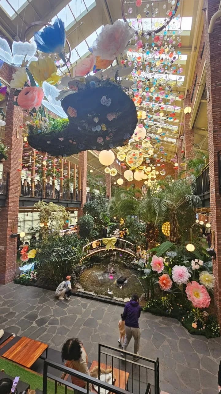 포레스트 아웃팅스 1층 분수가 나오는 연못과 작은 다리 위에서 사진 찍는 방문객들 | 하이제이에스비