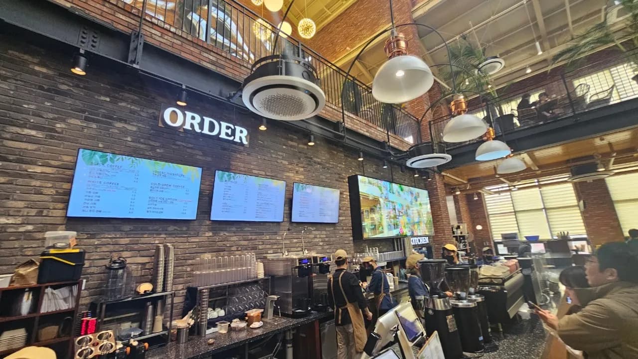 포레스트 아웃팅스 1층 ORDER 간판 아래 모니터 메뉴판 4개와 주문 대기 중인 카운터 전경 | 하이제이에스비
