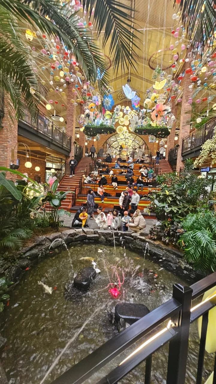 포레스트 아웃팅스 1층 리본 달린 다리와 야자수 사이 둥근 조명이 떠있는 정원 풍경 | 하이제이에스비