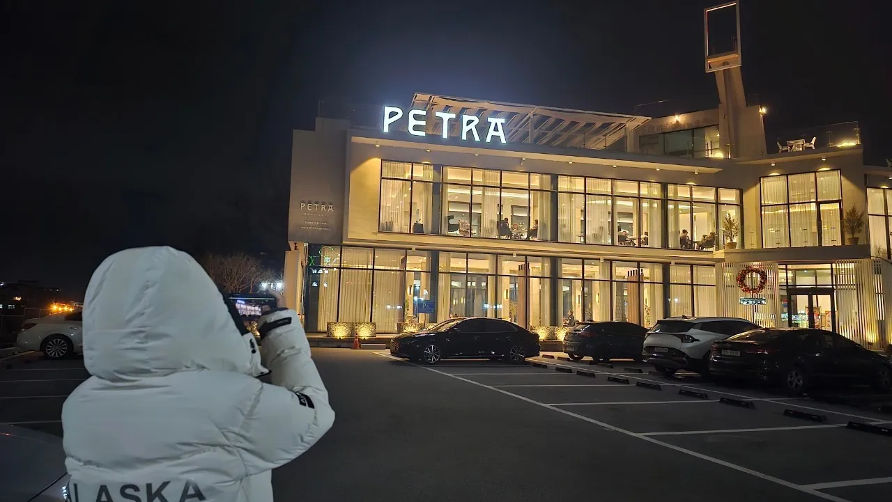 Ginin PETRA cafe daga gaba - gini na zamani mai bene biyu da gilashi da fitilu masu faɗi, daukar hoto da dare | 하이제이에스비