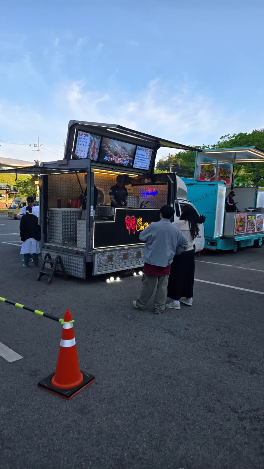 검은색 푸드트럭 앞에 줄 서 있는 사람들