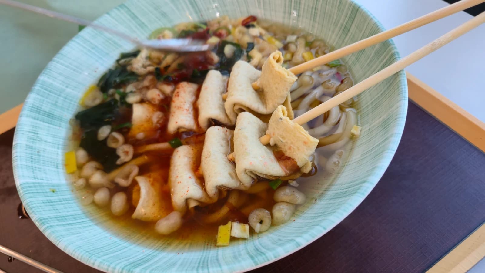 Chopsticks lifting udon noodles from the bowl