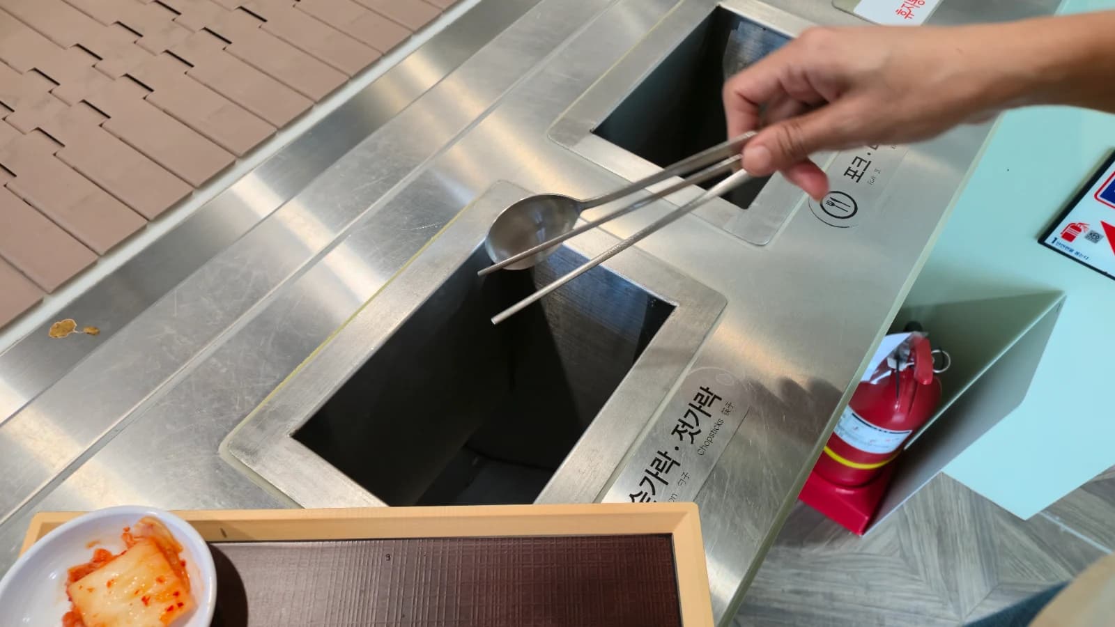 Stainless steel utensil return station with sorted spoons and chopsticks