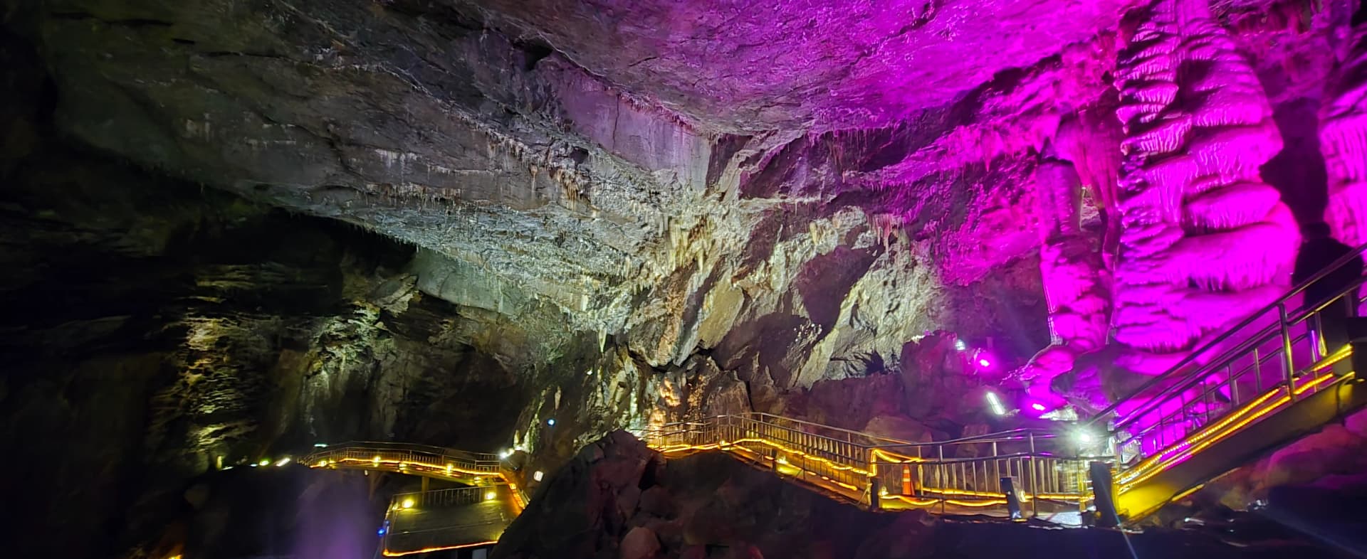 Stalaktit bergantung di siling batu dan tiang batu besar diterangi cahaya ungu | 하이제이에스비