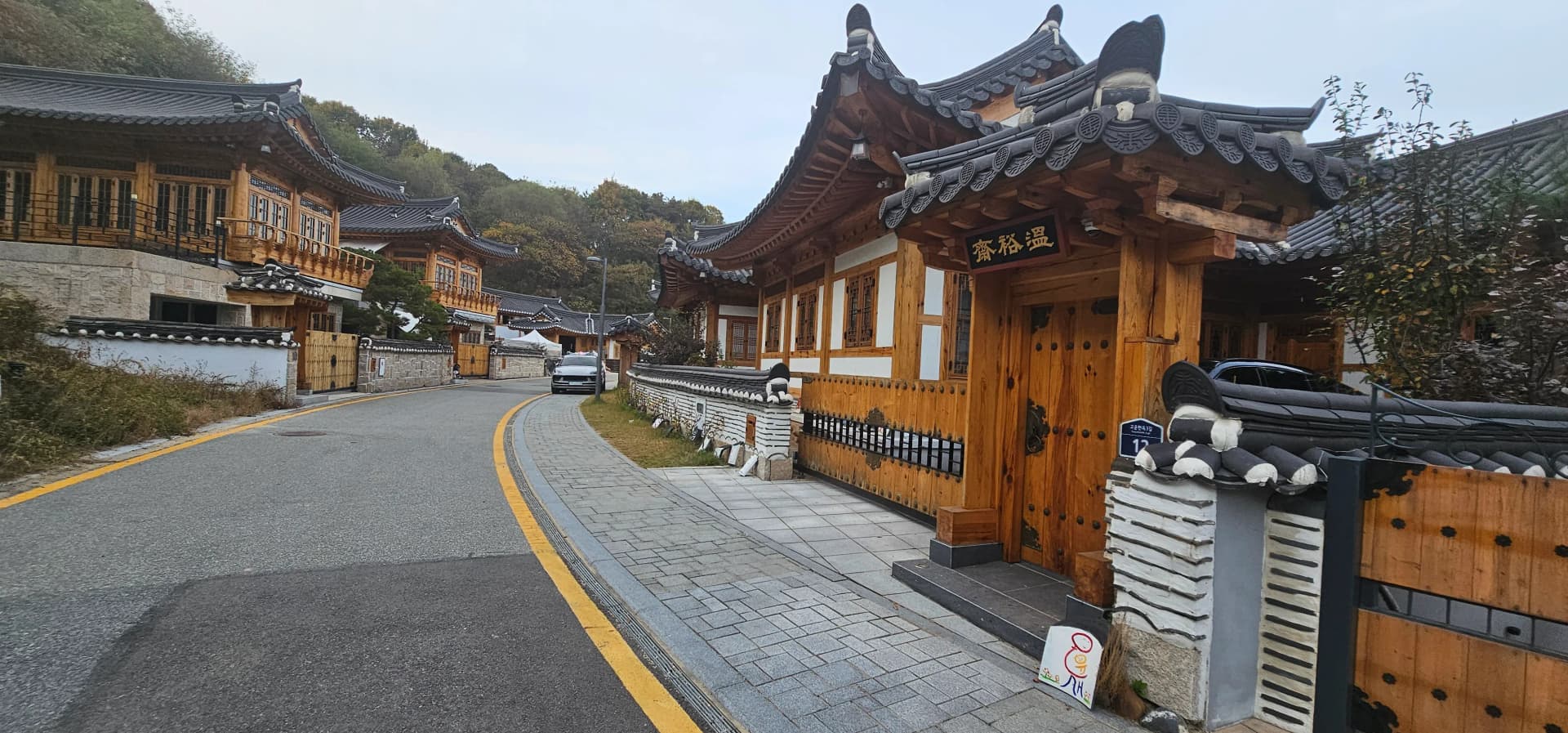 석축 위에 지어진 한옥 주택 — 소나무 사이로 기와지붕이 보인다 | 하이제이에스비
