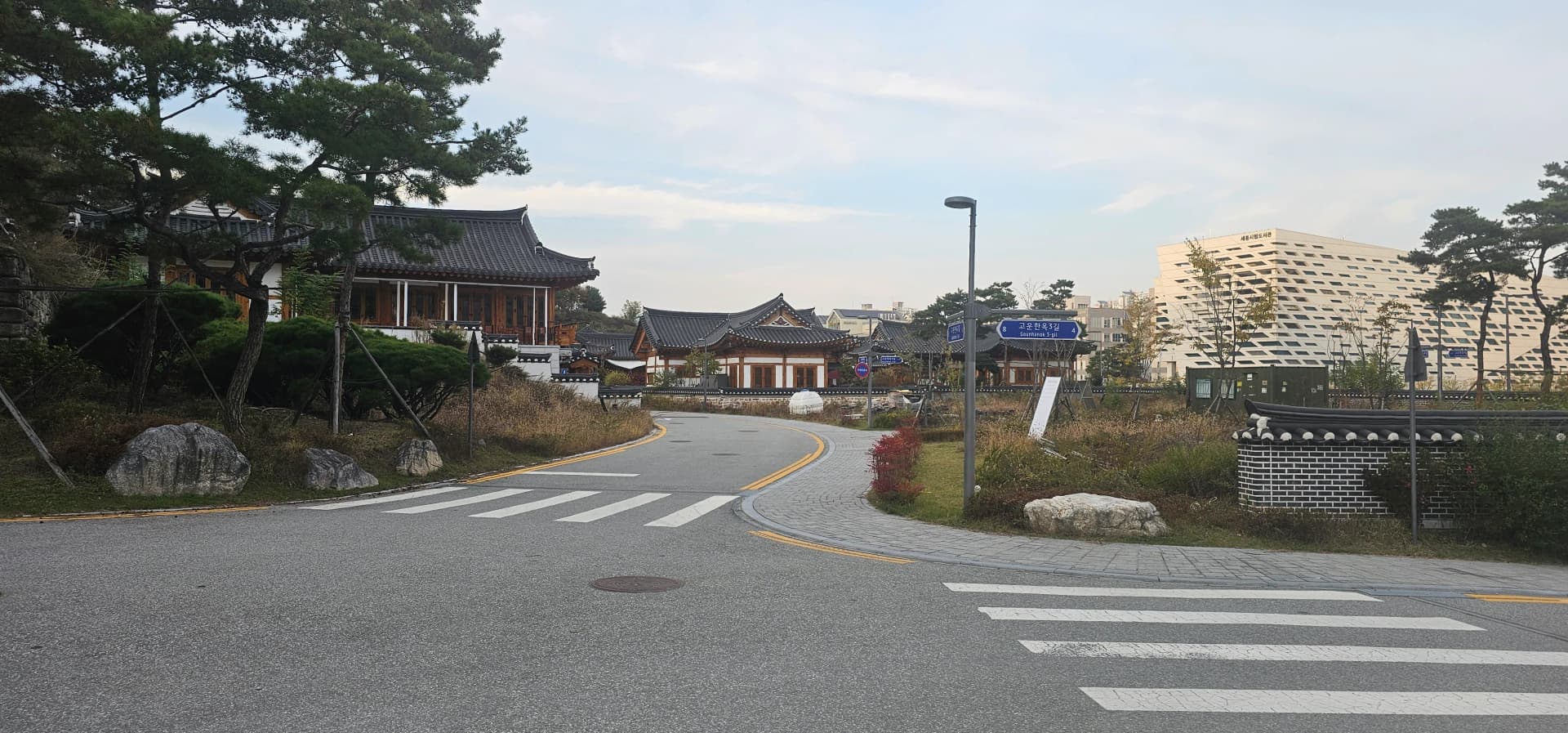 기와 조각과 벽돌을 섞어 쌓은 전통 문양 담장 — 석축 위에 소나무가 올라와 있다 | 하이제이에스비